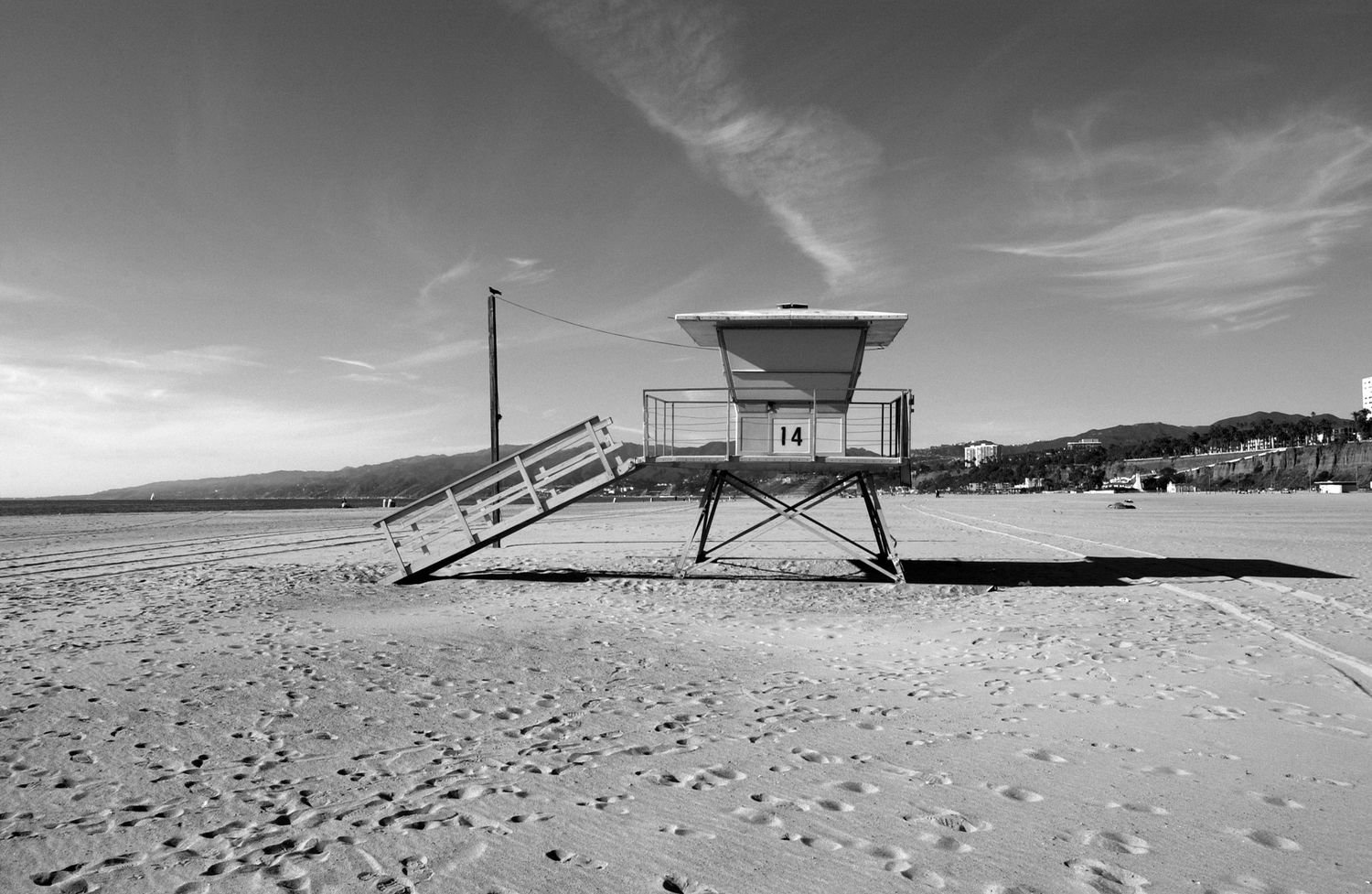 Panoramic black and white beach landscape with lifeguard tower and sand dunes.