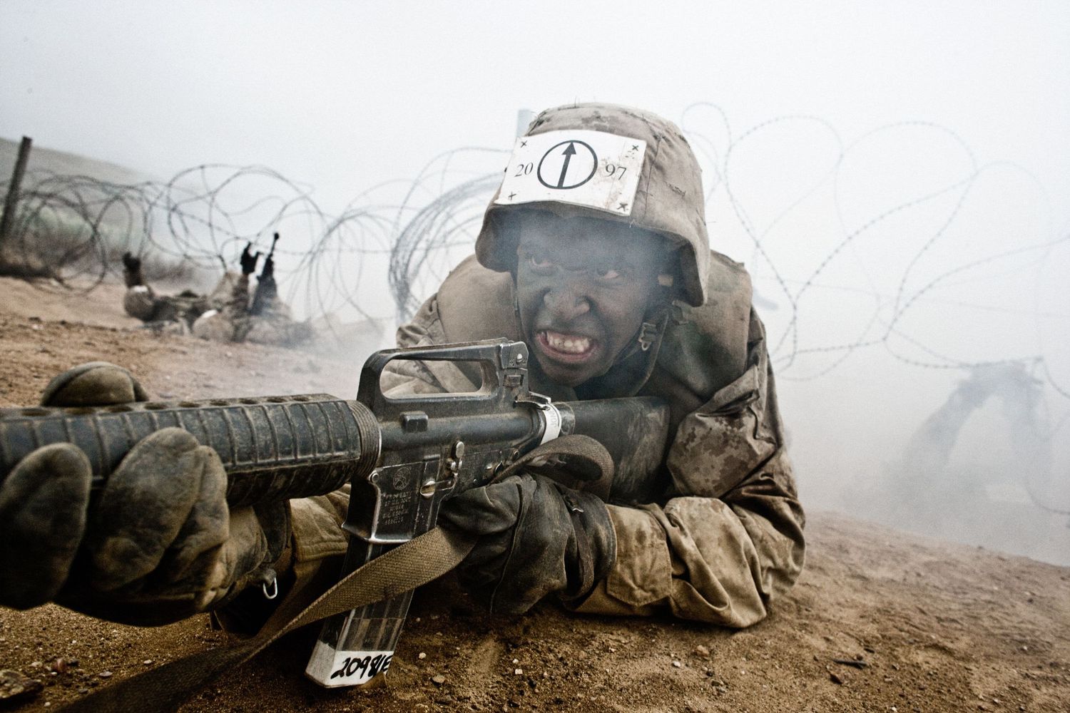 Military personnel conducting combat exercises in smoky battlefield conditions.