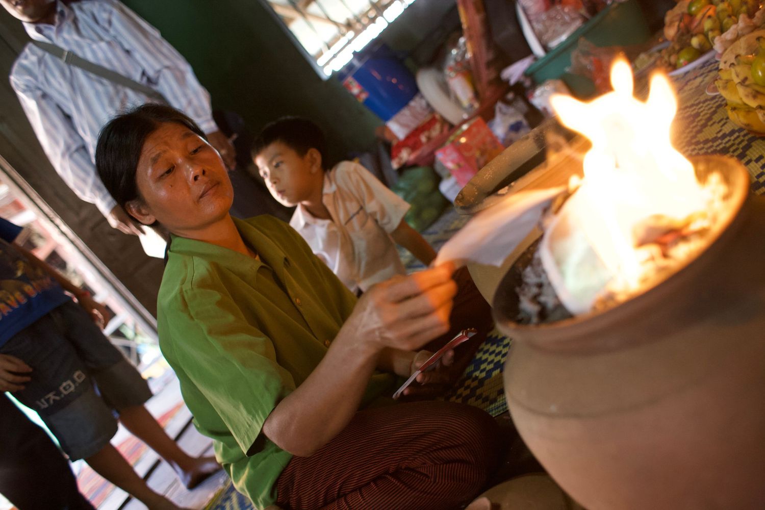 Group of people gathered around a bright flame or fire at night.