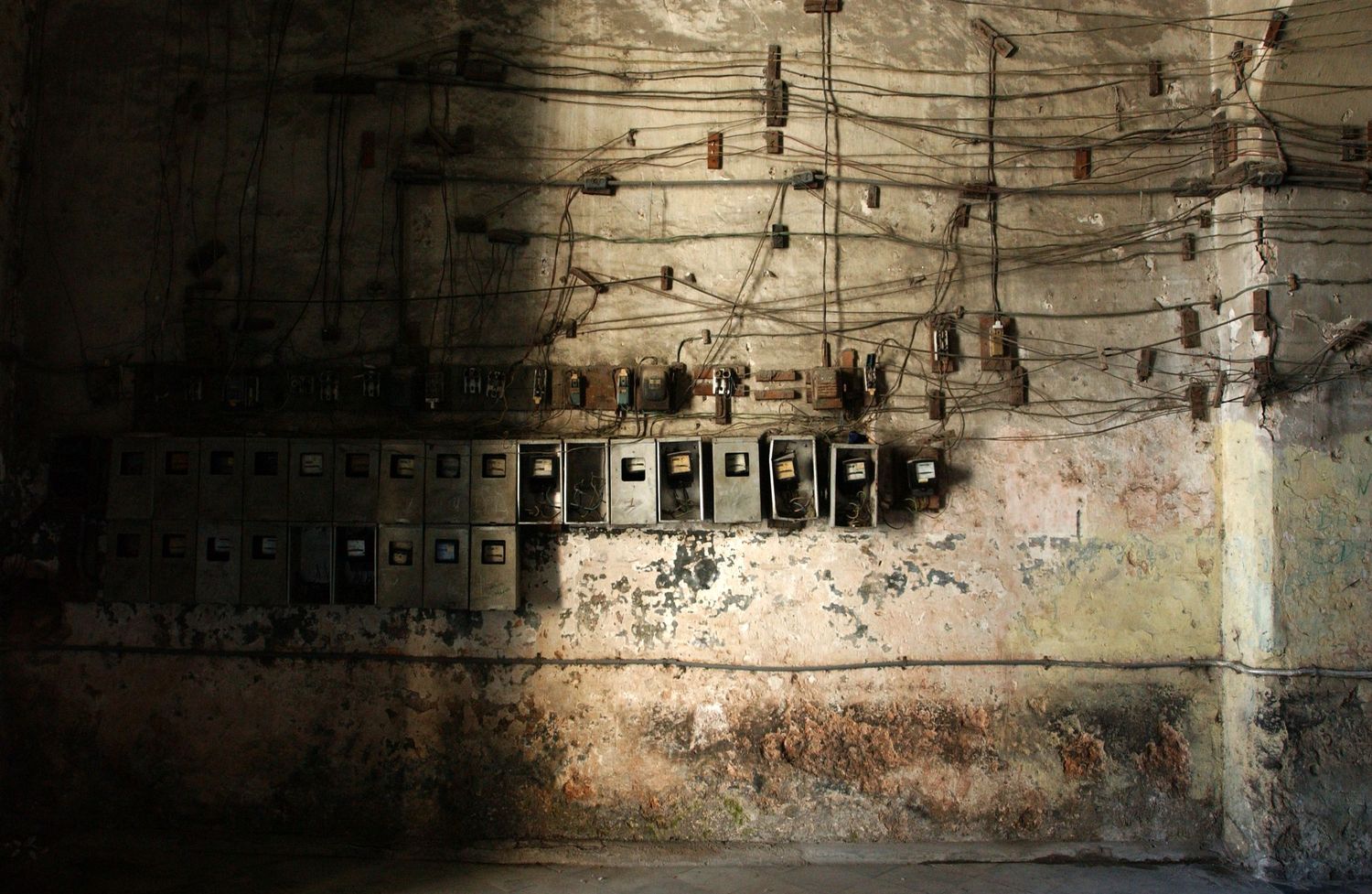 Weathered stone wall with electrical fixtures and peeling paint texture.