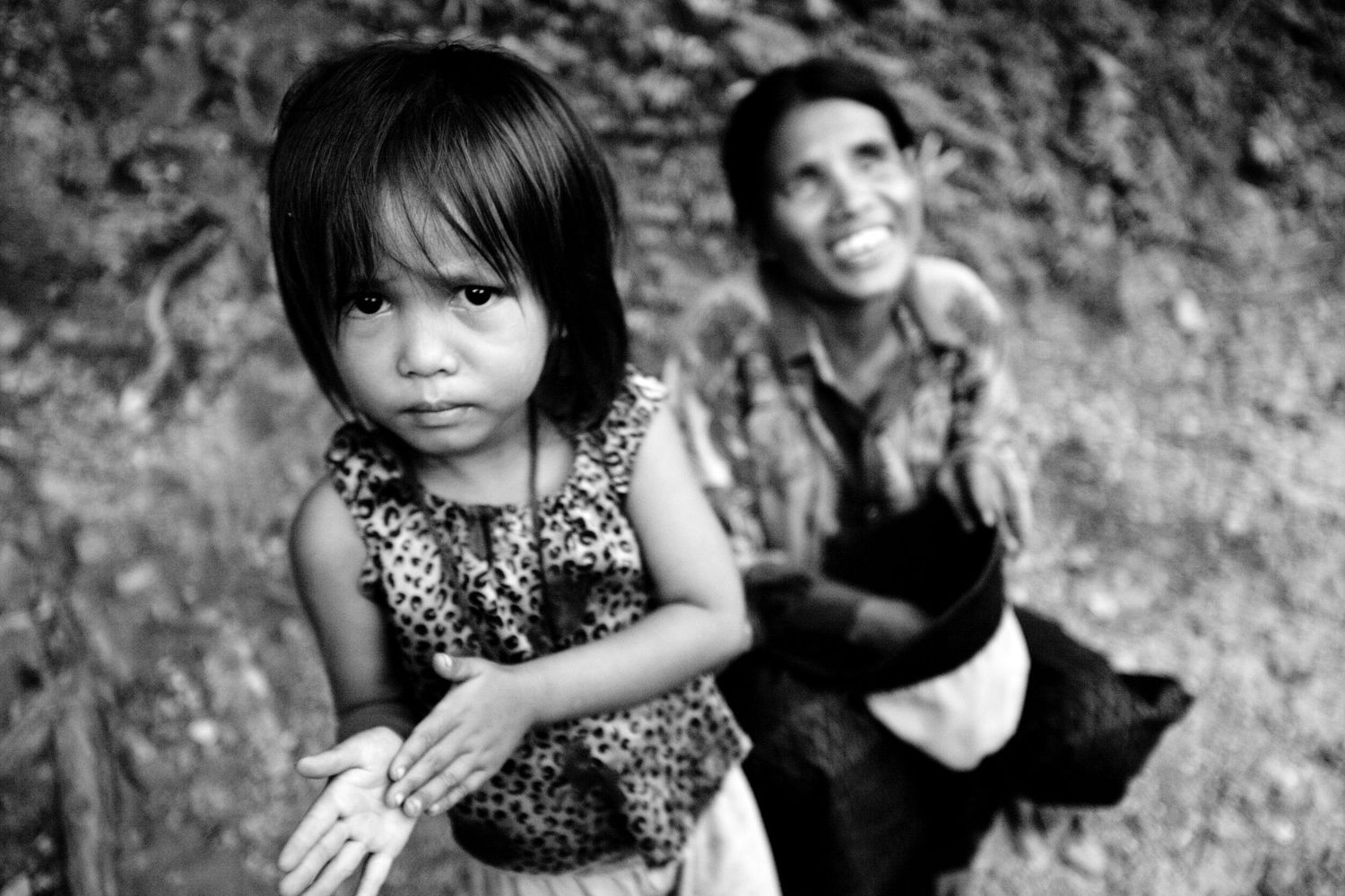 Children in casual attire playing outdoors against a rocky backdrop.
