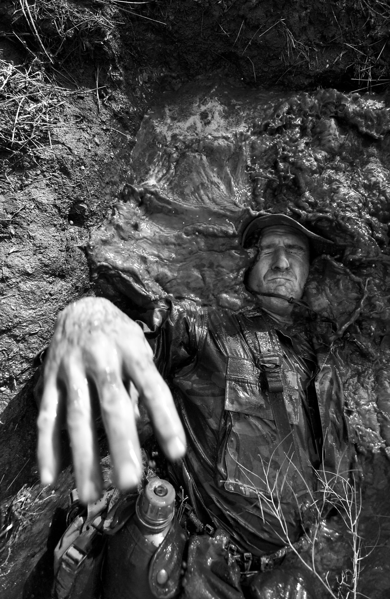 Close-up black and white shots of hands emerging from textured rock surfaces.