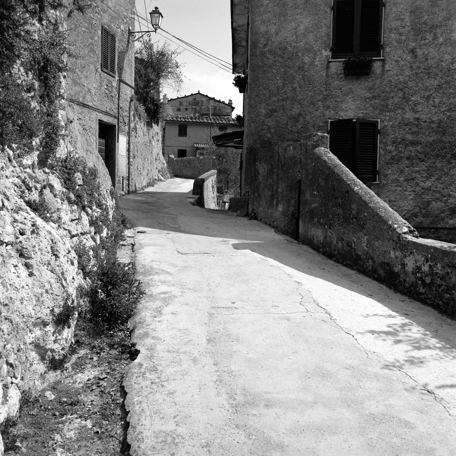 Narrow stone alleyways and streets in an old Mediterranean village shown in black and white.