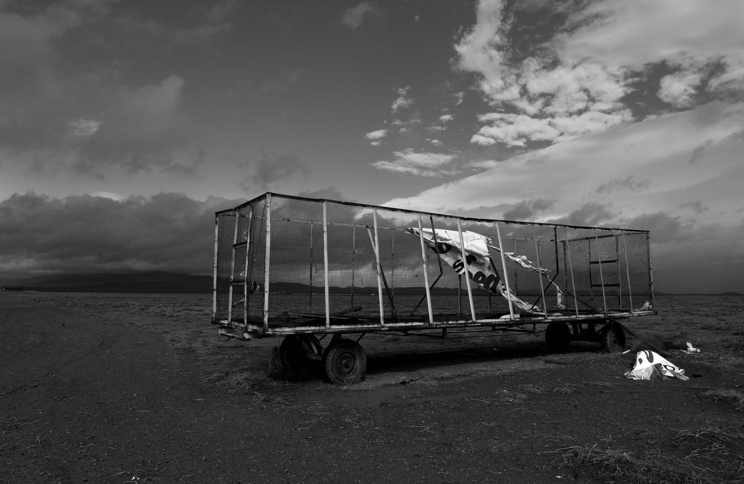 Abandoned mining structures and equipment scattered across a desolate hillside in black and white.