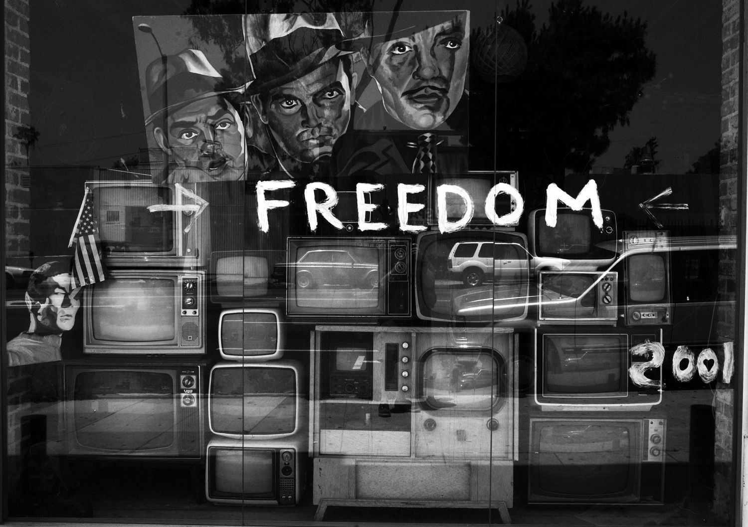 Black and white mural with the word FREEDOM painted above a wall of vintage television sets.