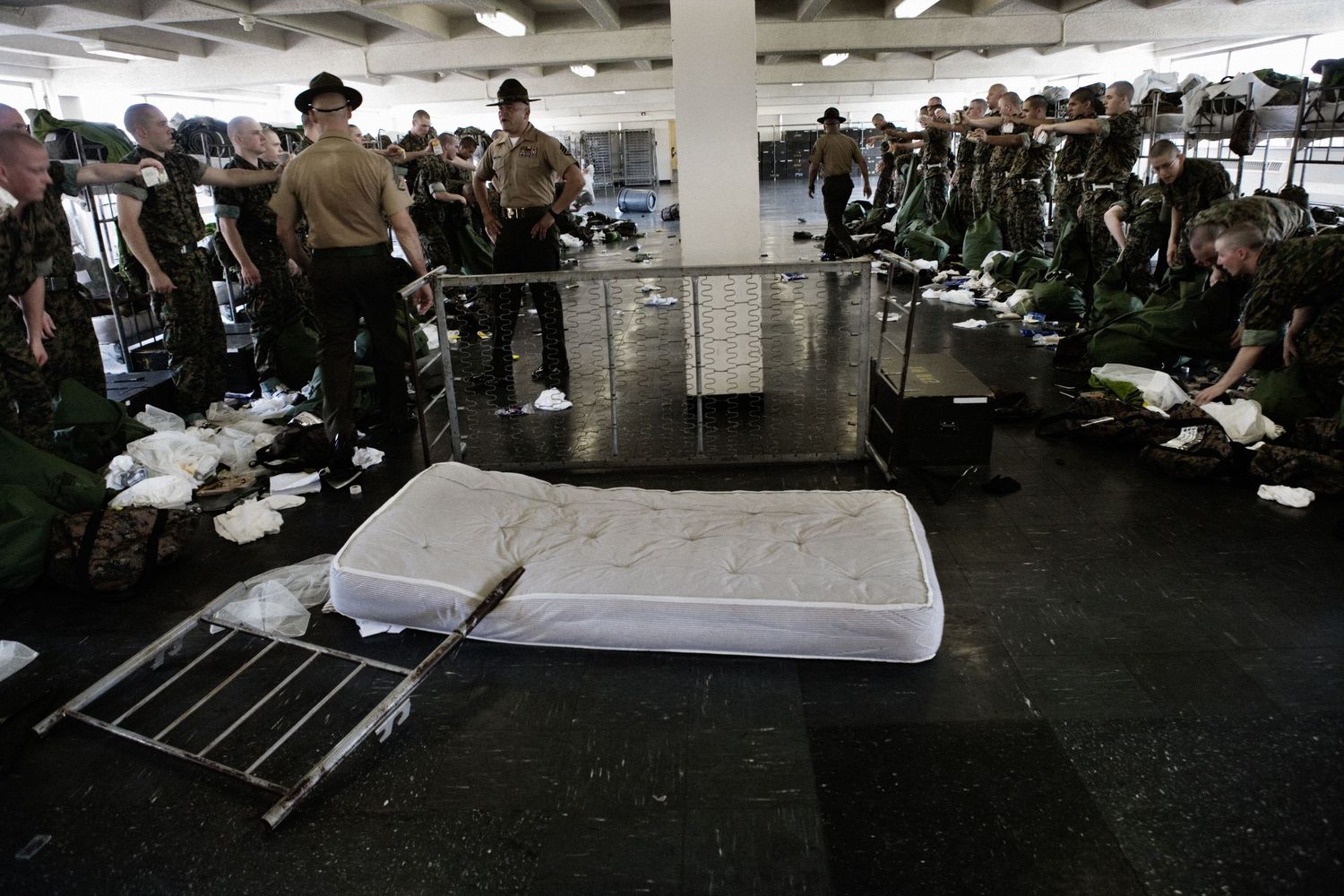 Military recruits resting in bunks inside a crowded barracks dormitory.