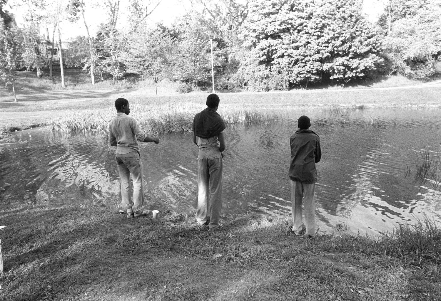 People walking along a riverbank or waterside path in a natural setting.
