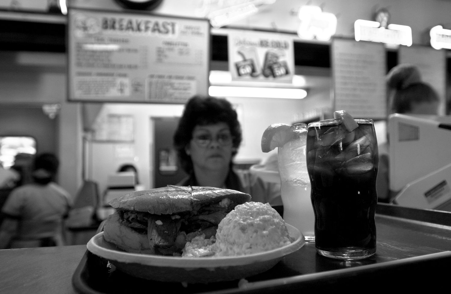 Black and white photo of a restaurant counter with plates of food and drinks.