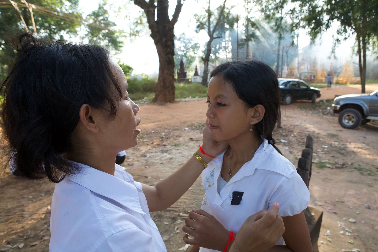Medical professionals in white coats examining patients outdoors under trees.
