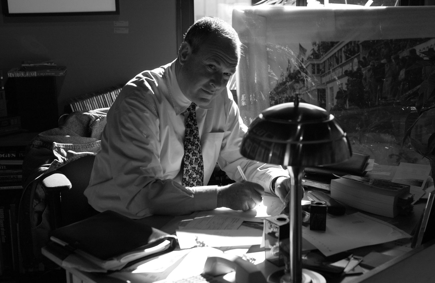 Person working at a desk under focused lighting in a dark room.