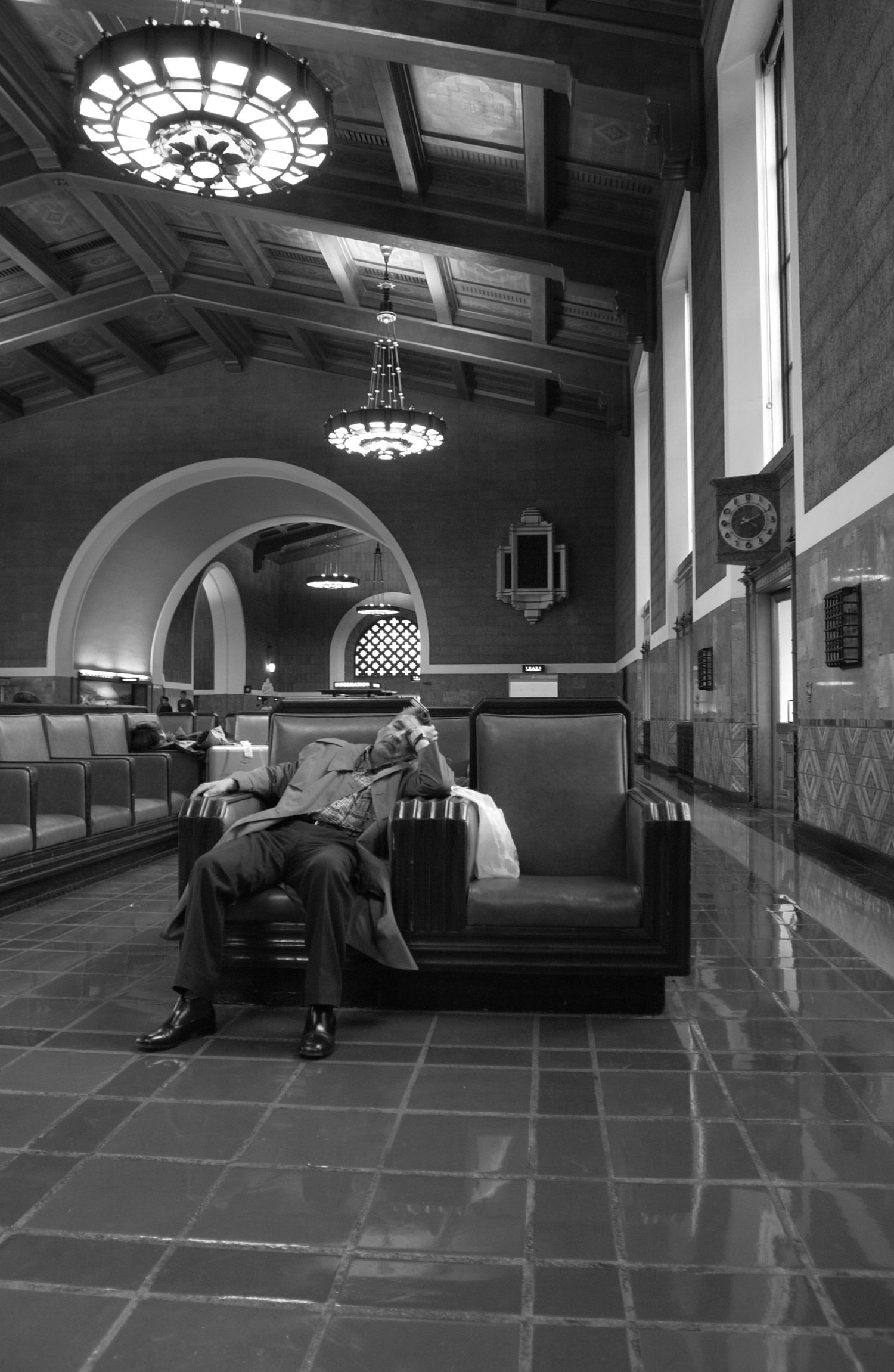 Black and white photos of empty train or subway station interior with ornate ceiling lights.