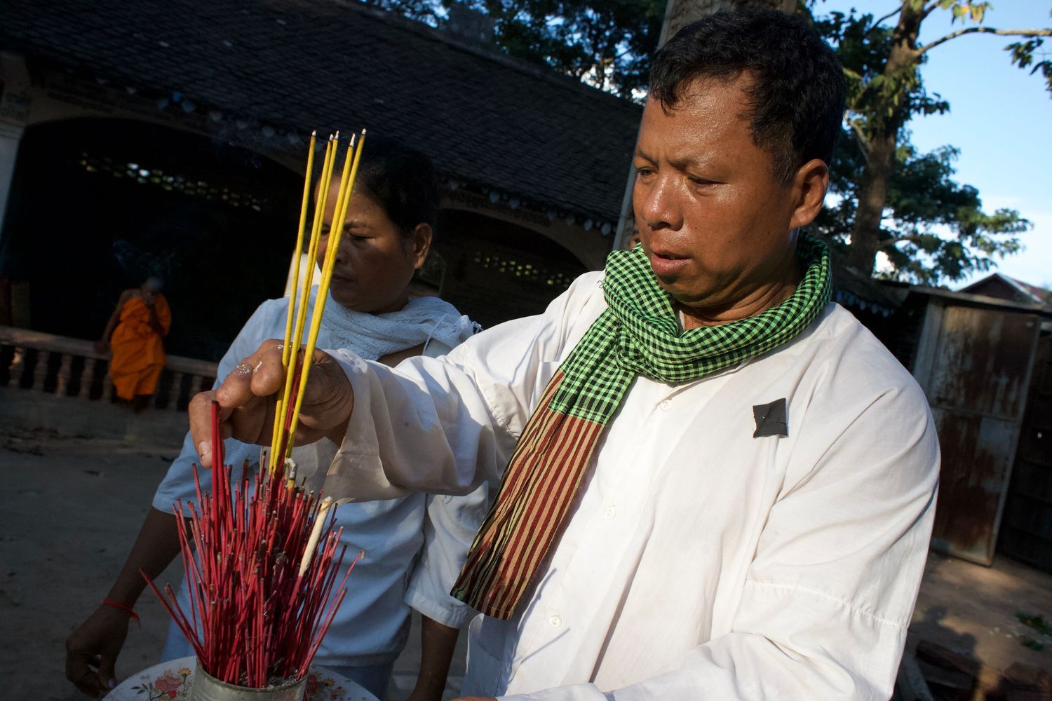 Group wearing traditional white garments and green scarves at outdoor gathering.