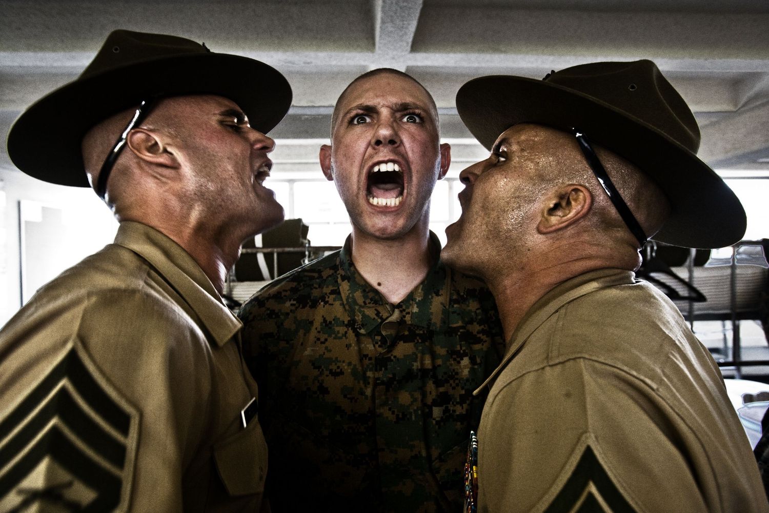 Military instructors in uniform display intense expressions during training session.