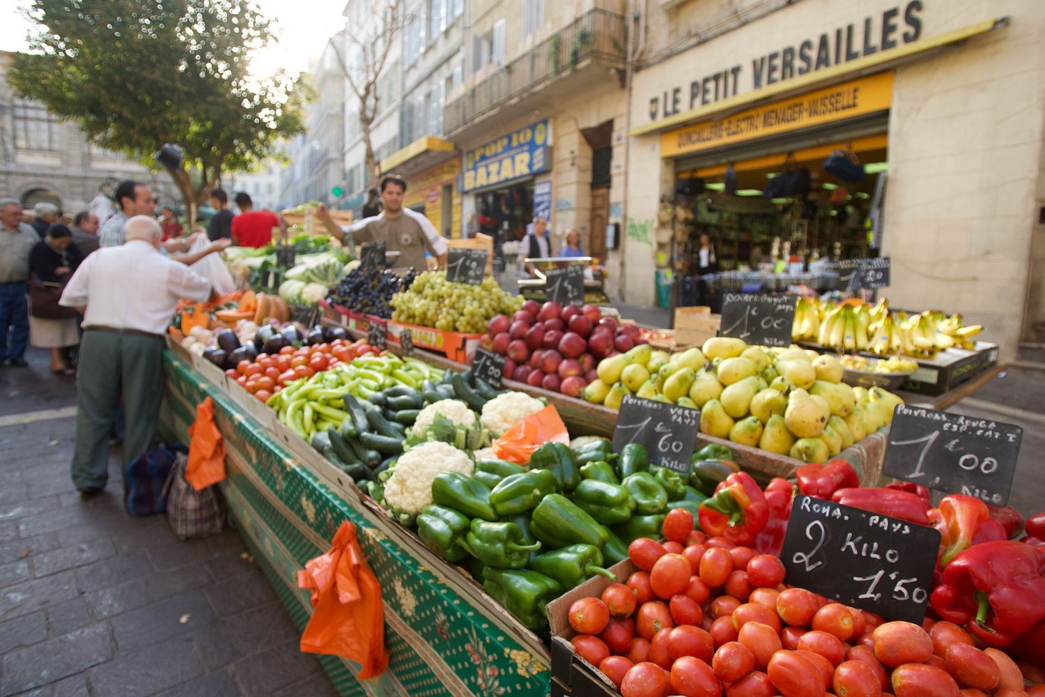 Colorful produce market stall displaying fresh fruits and vegetables on street in France.