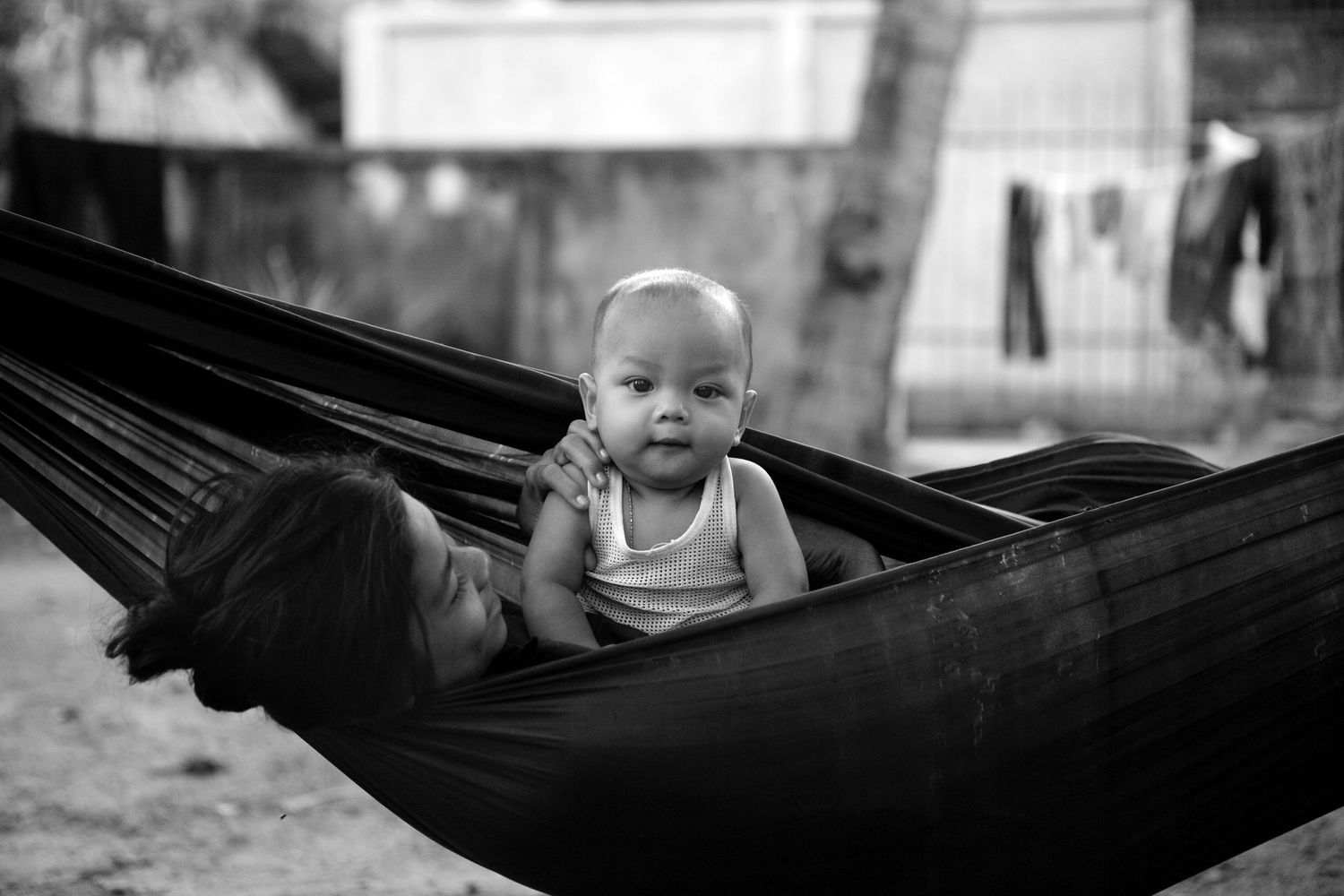 Baby resting peacefully in a dark hammock photographed in black and white.