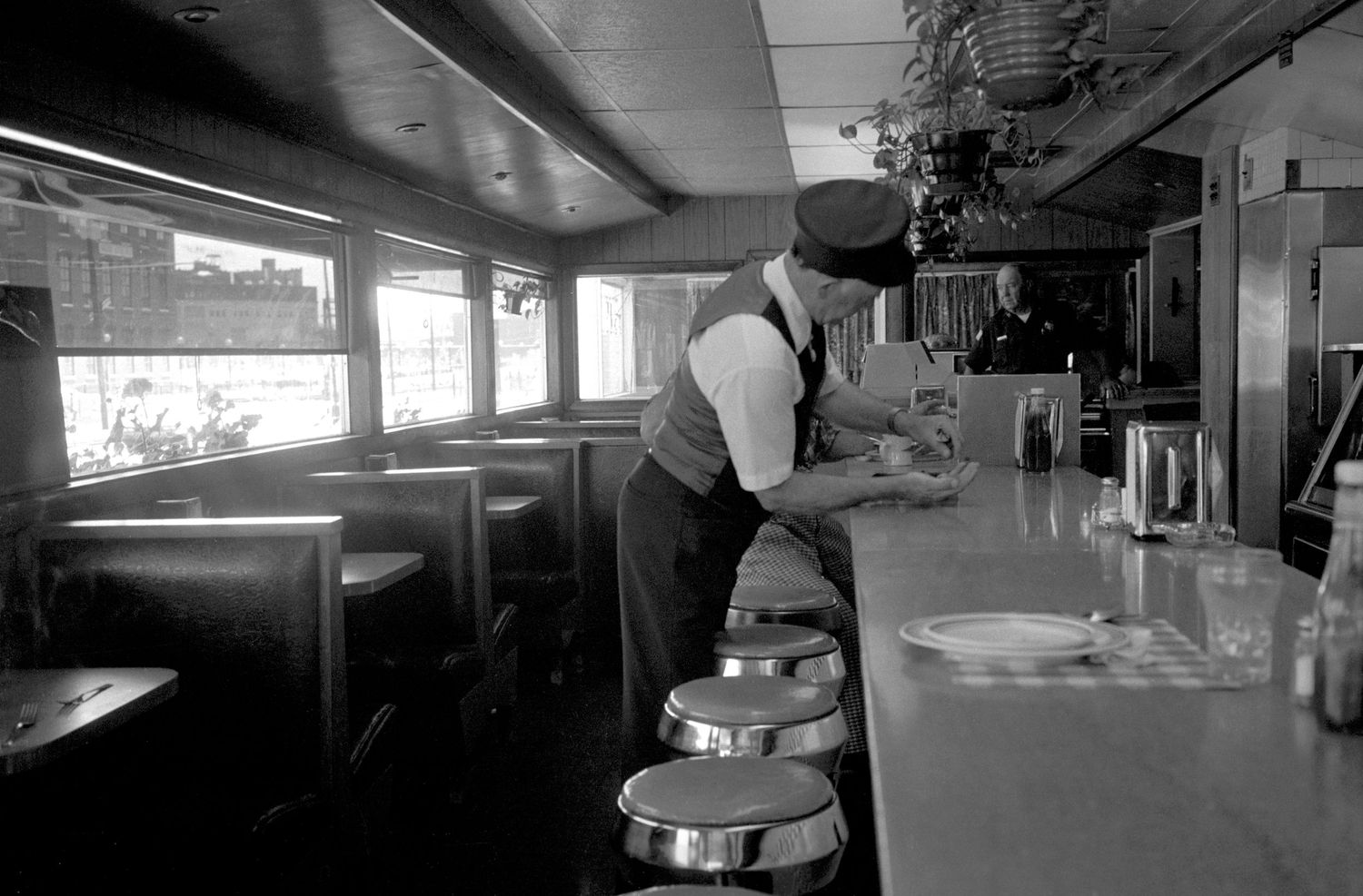 Interior view of a diner counter with stools and fluorescent lighting.
