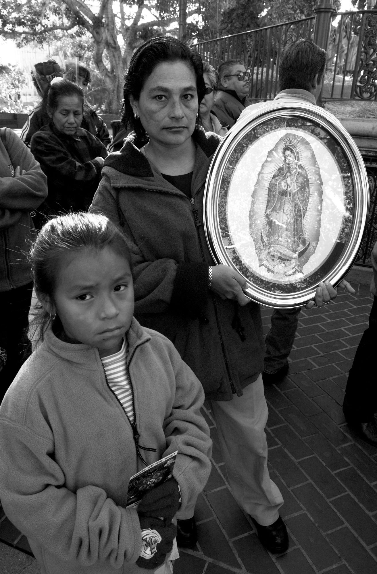 People gathered outdoors holding decorative religious plates.