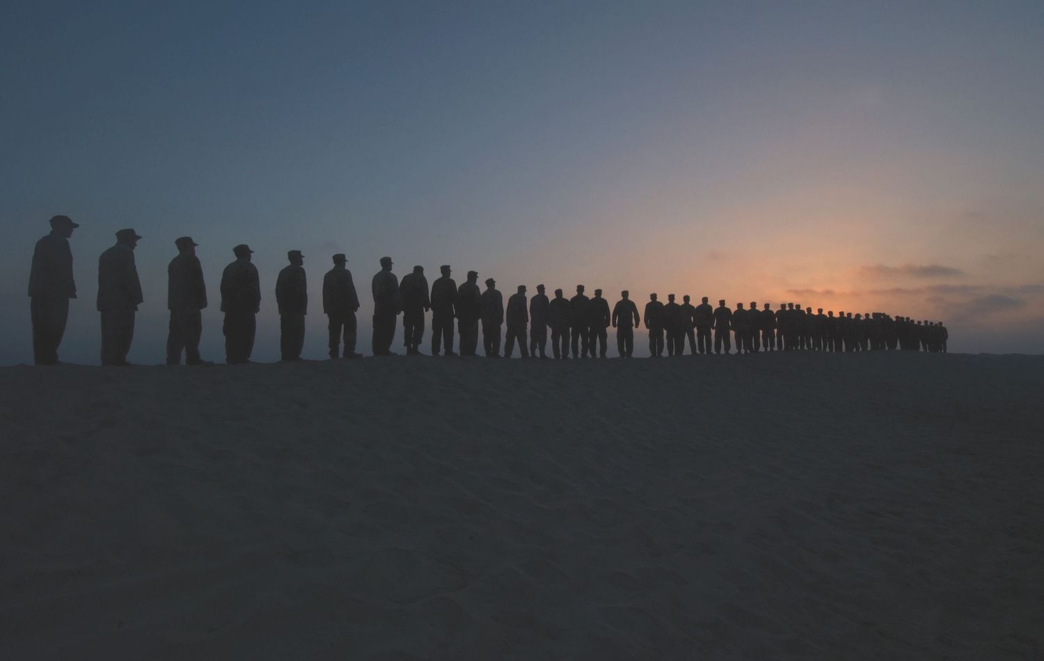 Class 246 of Marines Crest on a sand berm to salute the sunset. Photograph by Richard D. Schoenberg