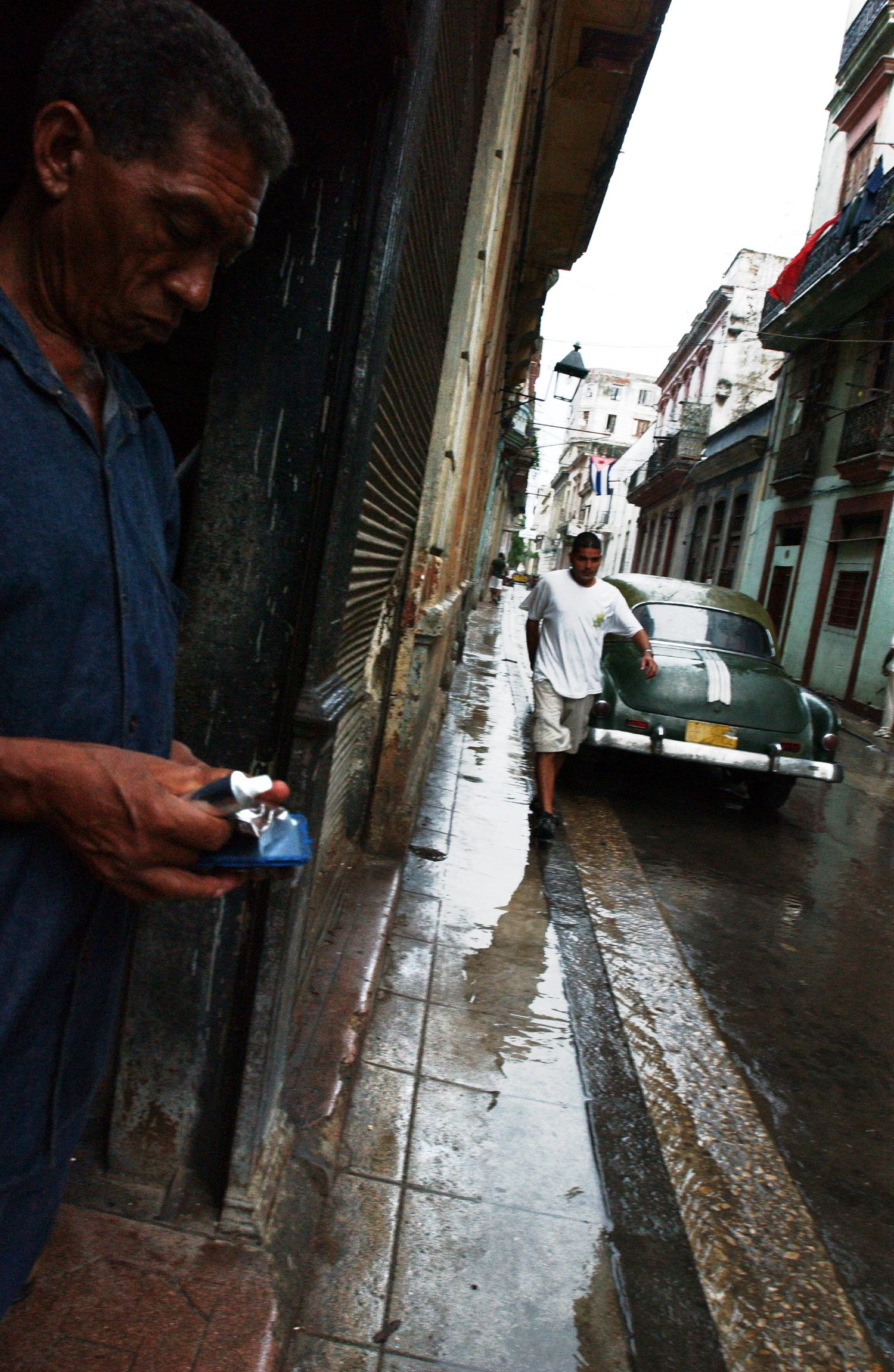Wet cobblestone street scene with person in dark clothing holding something.