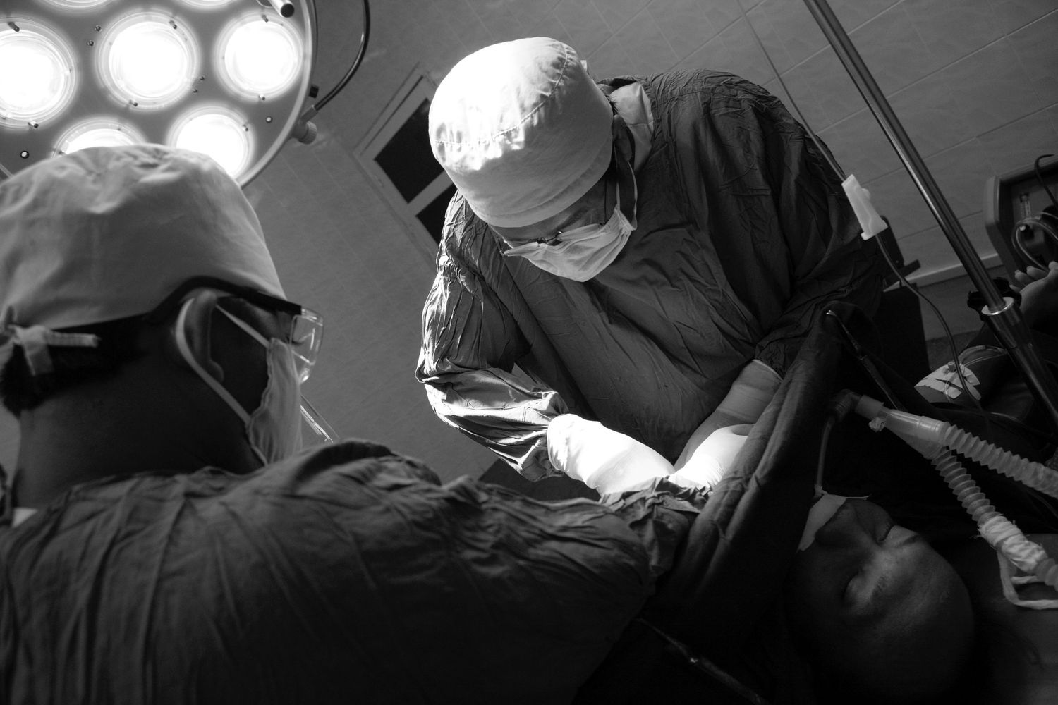 Operating room scene with surgical lights and medical staff at work.