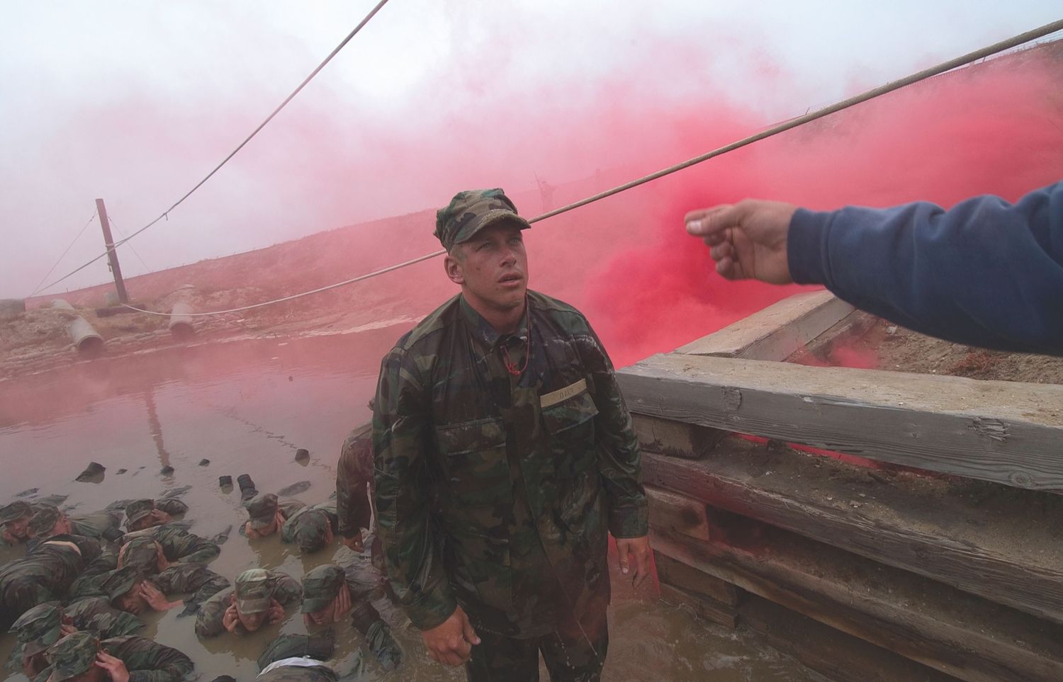 Military training exercise conducted on a reddish-tinted terrain with multiple personnel.