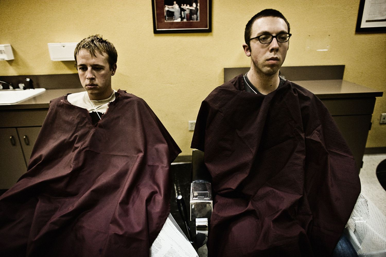 Several military recruits receiving haircuts in a barbershop setting.