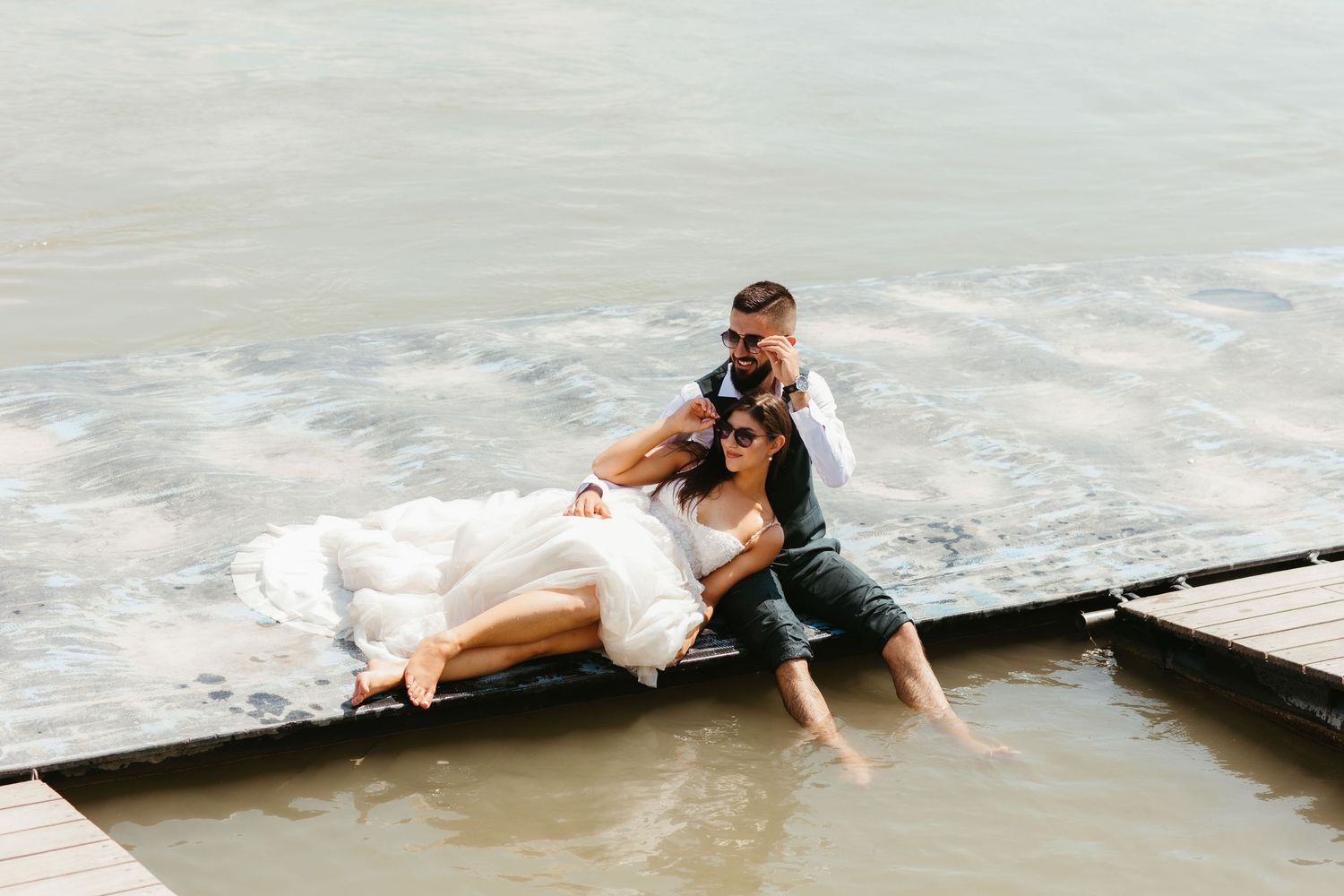 An adventurous couple poses on a rocky beach as ocean waves crash around them creating a dramatic setting.