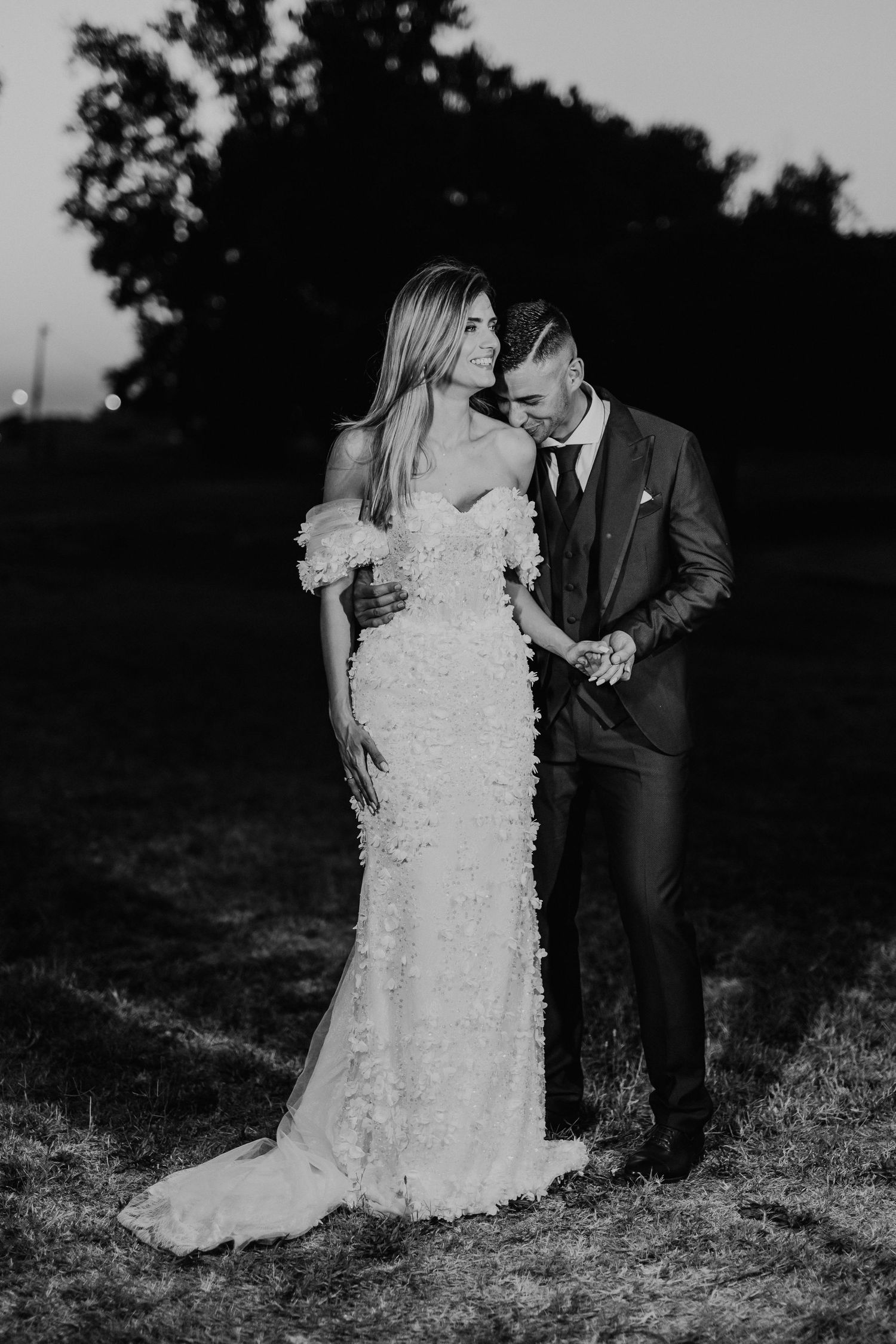 Black and white wedding portrait showing intimate moment between couple in elegant attire.