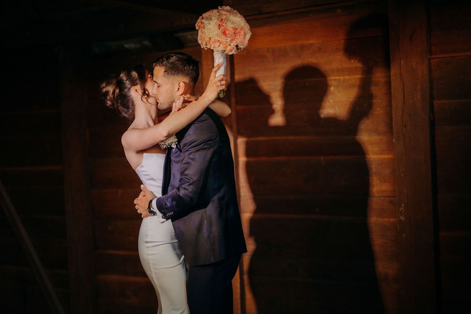 A couple shares an intimate dance in a rustic wooden barn setting with romantic lighting.