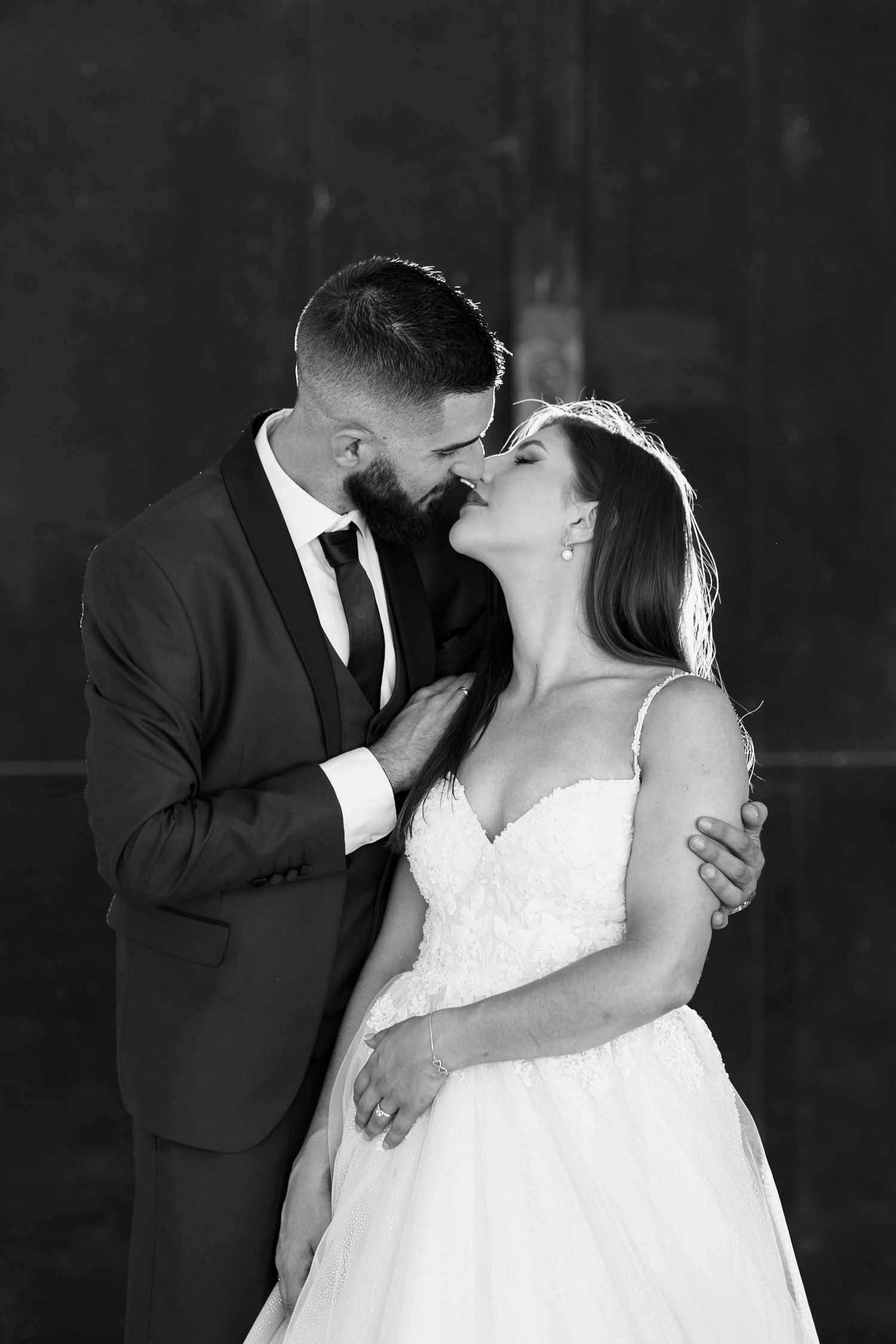 A romantic black and white portrait of a bride and groom sharing an intimate moment during their wedding.