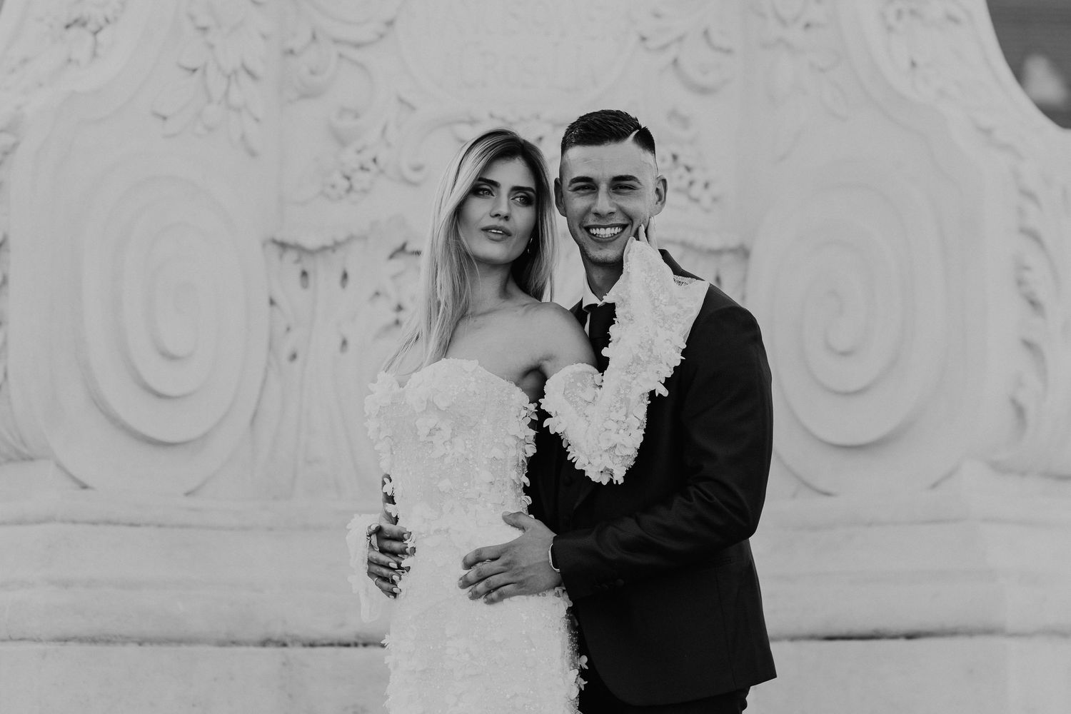 Black and white wedding portrait against ornate architectural details.