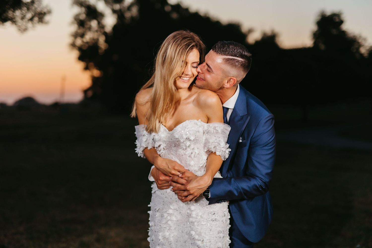 Intimate wedding portrait of newlyweds sharing tender moment during golden hour photography session.