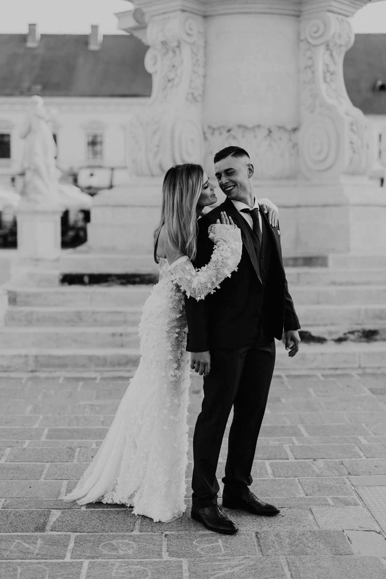 Black and white wedding photo captured against classical architectural backdrop.