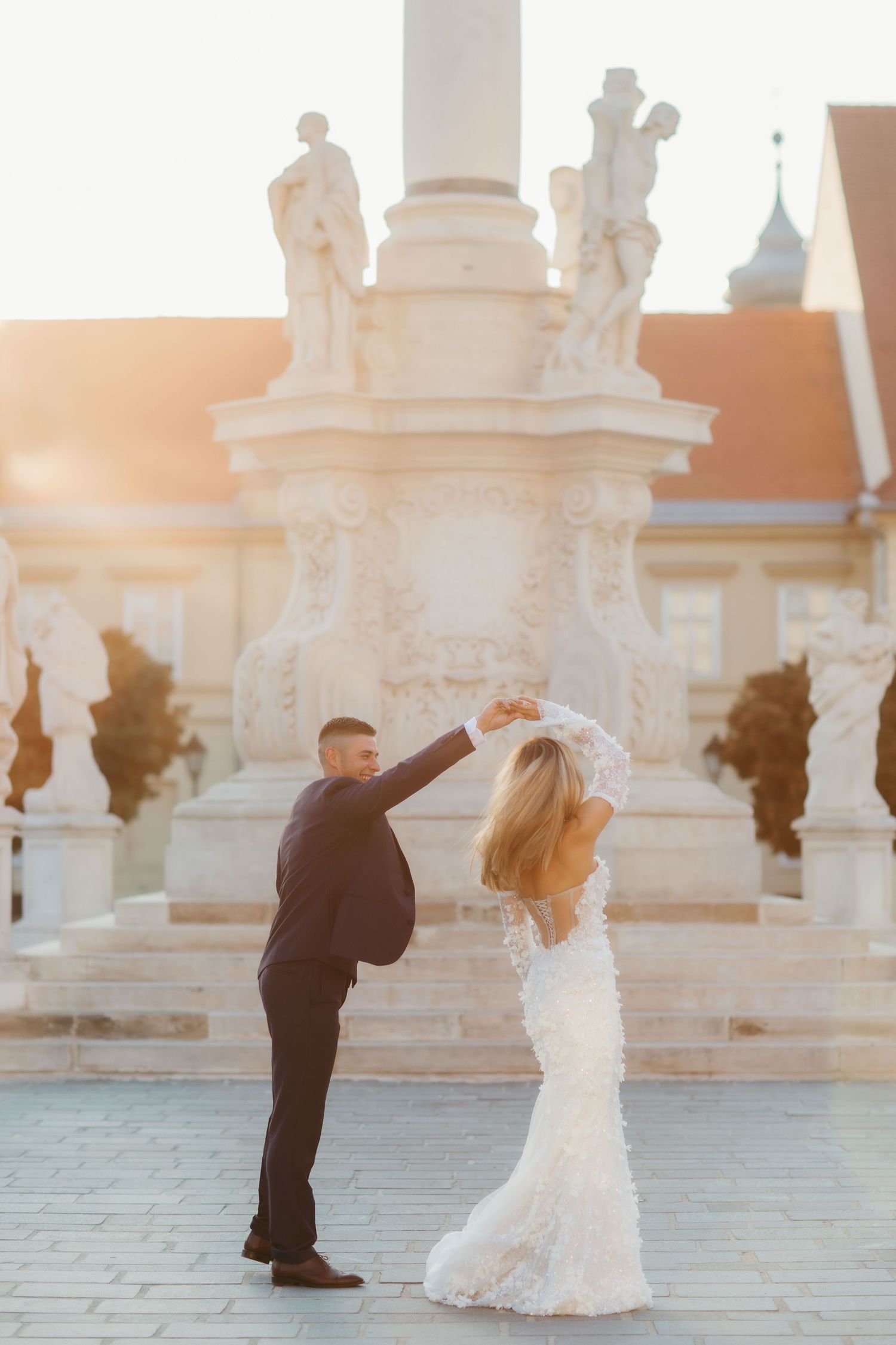 Wedding couple performs a dance twirl in front of architectural landmarks.