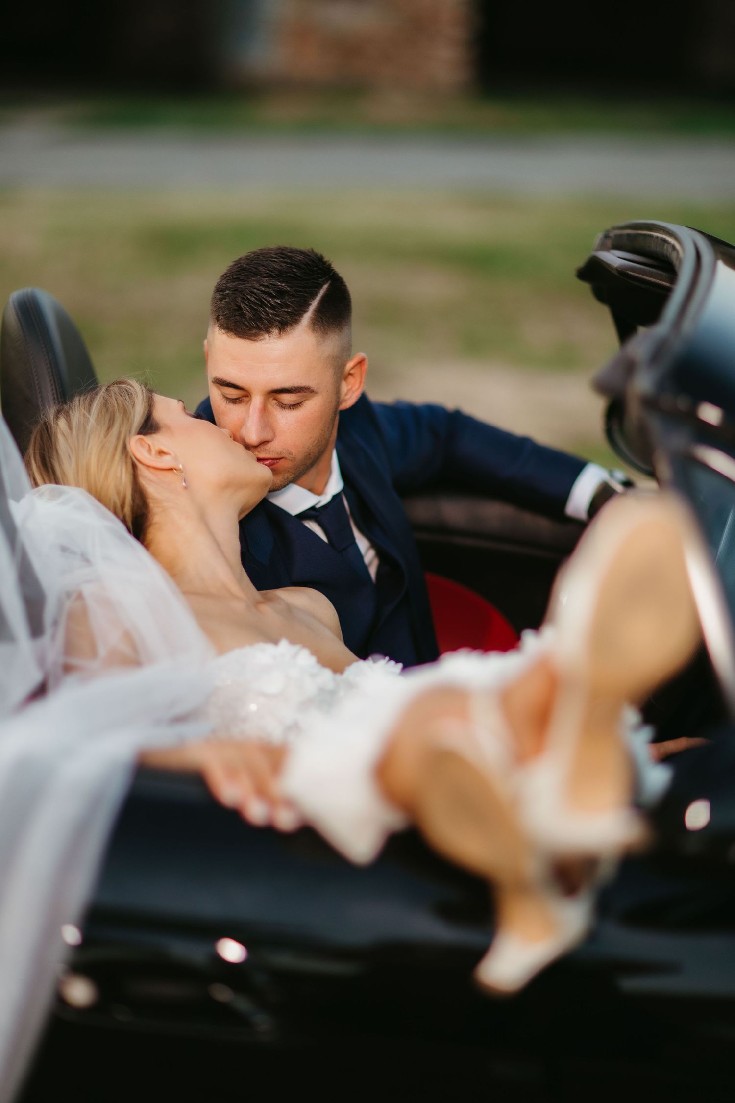 Intimate wedding moment captured in convertible with bride in white lace dress.