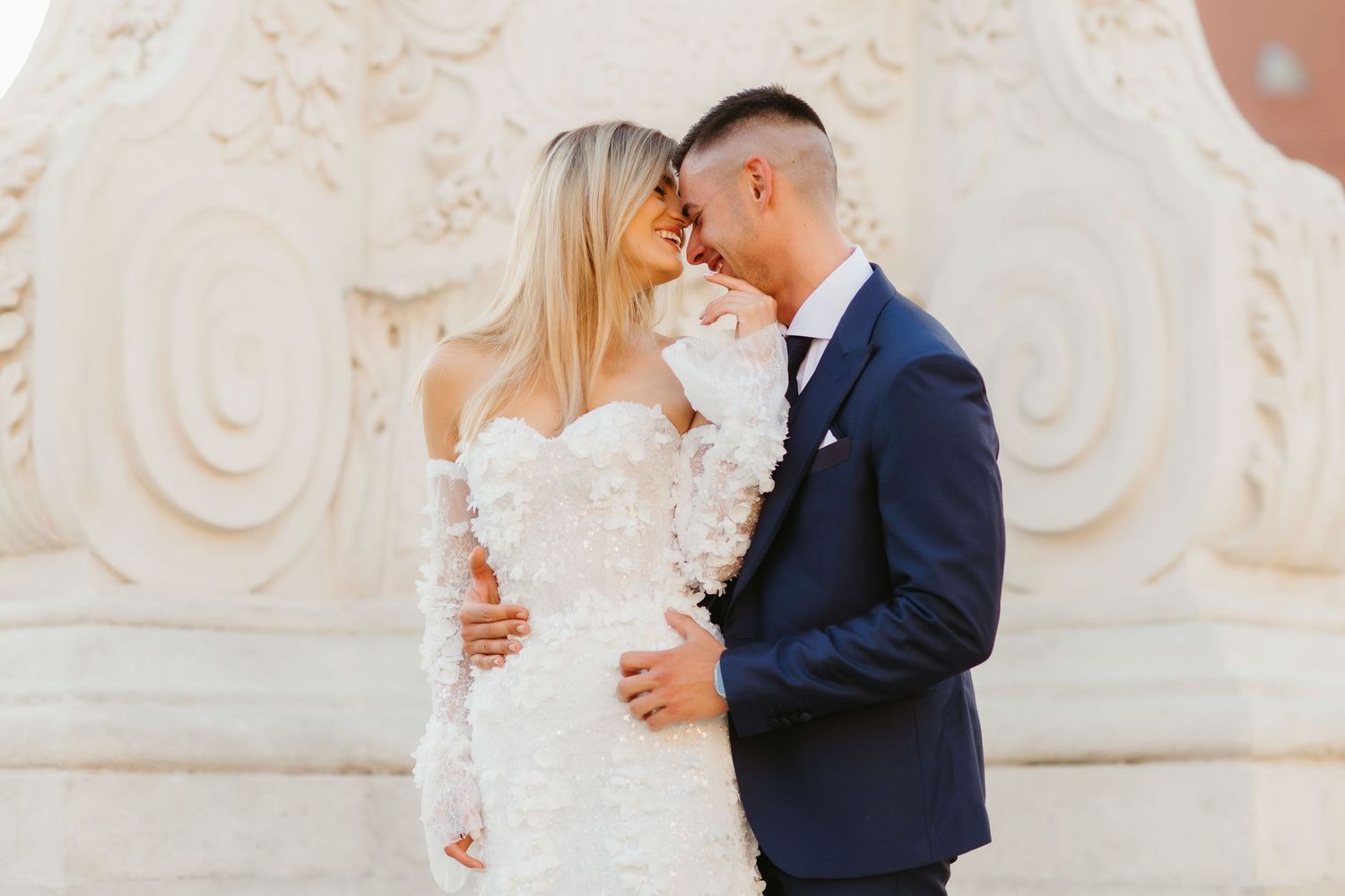 Tender wedding portrait against classical architecture in warm sunlight.