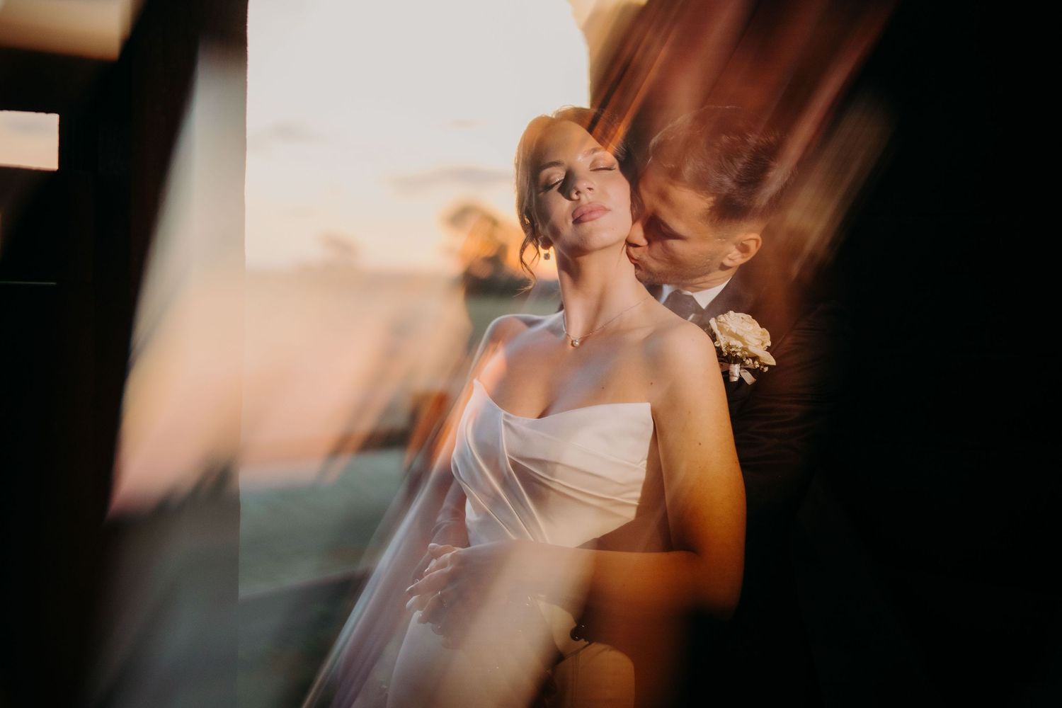 An intimate wedding moment captured through blurred glass with warm lighting and romantic atmosphere.