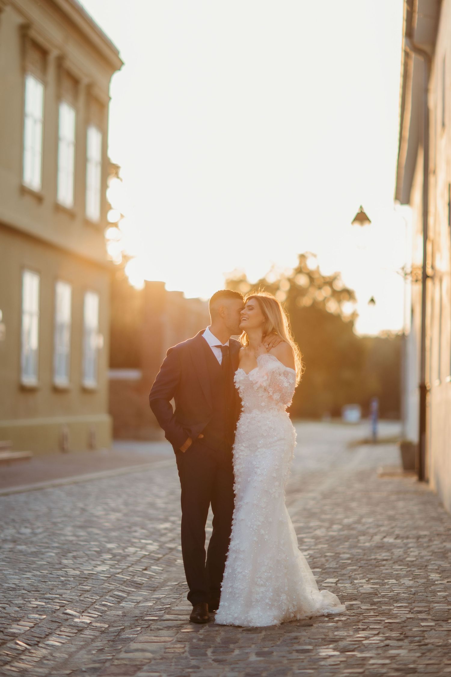 Intimate wedding moment captured on historic European street during sunset.