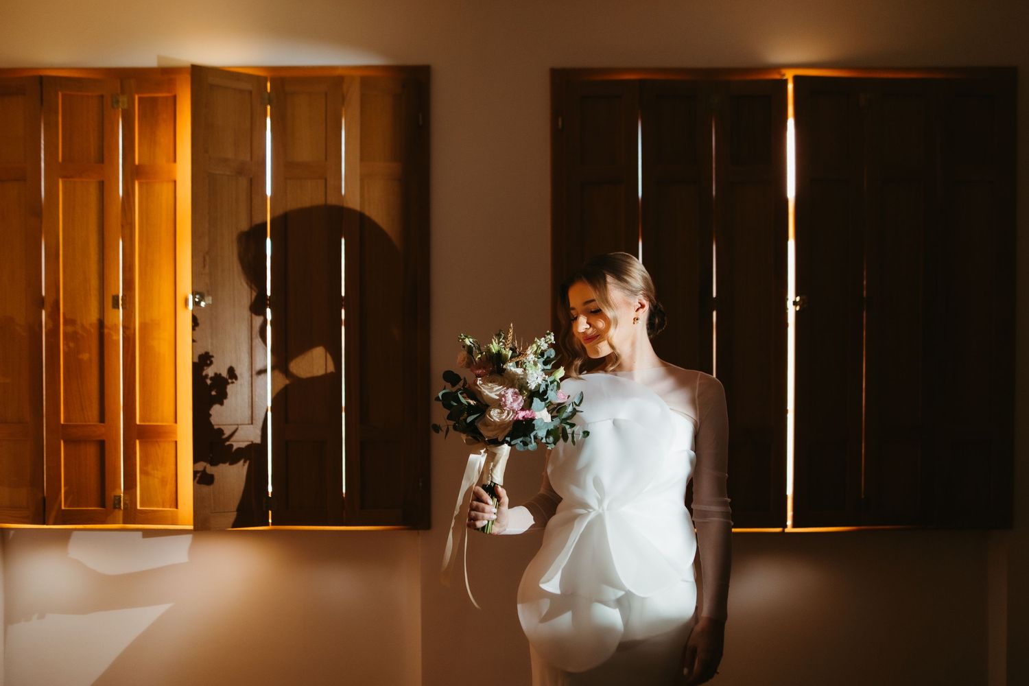 Artistic wedding photography utilizing dramatic window lighting and shadows.