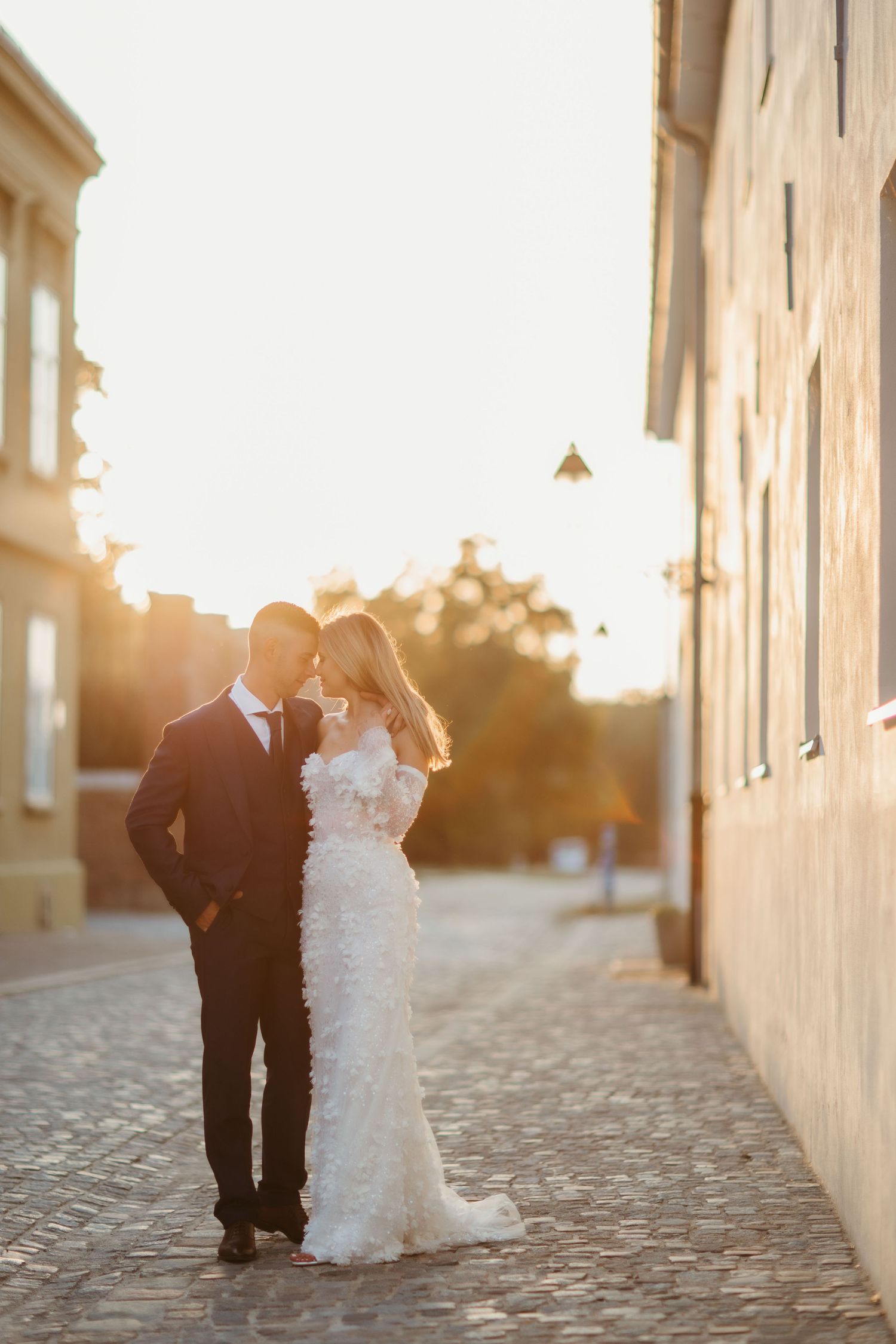 Golden hour wedding photo with couple standing between classic European buildings.
