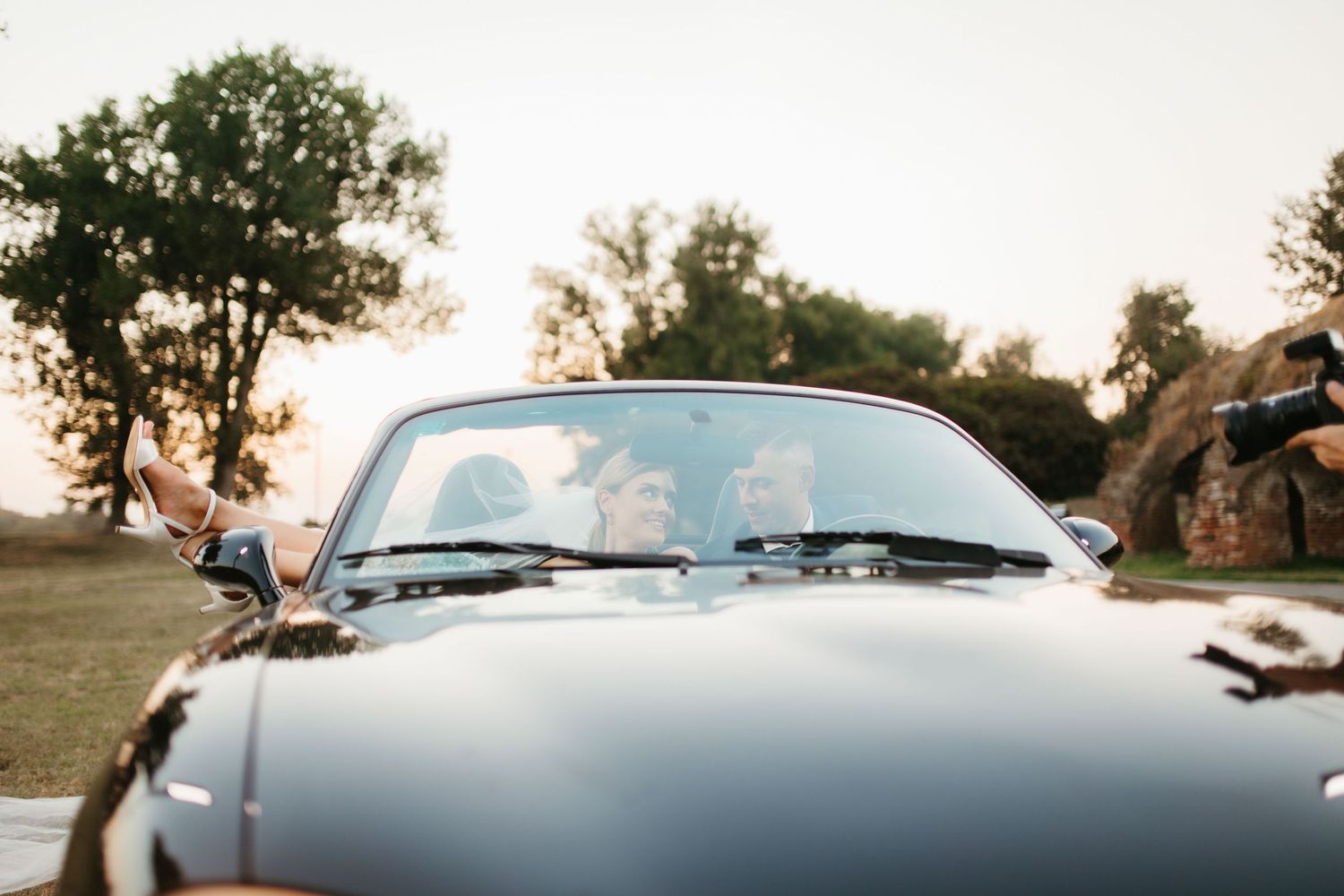 Black Mazda Miata convertible photographed from front during wedding photoshoot at sunset.