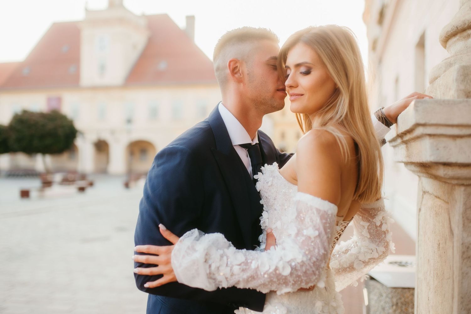 Intimate wedding portrait against historic European architecture in golden light.