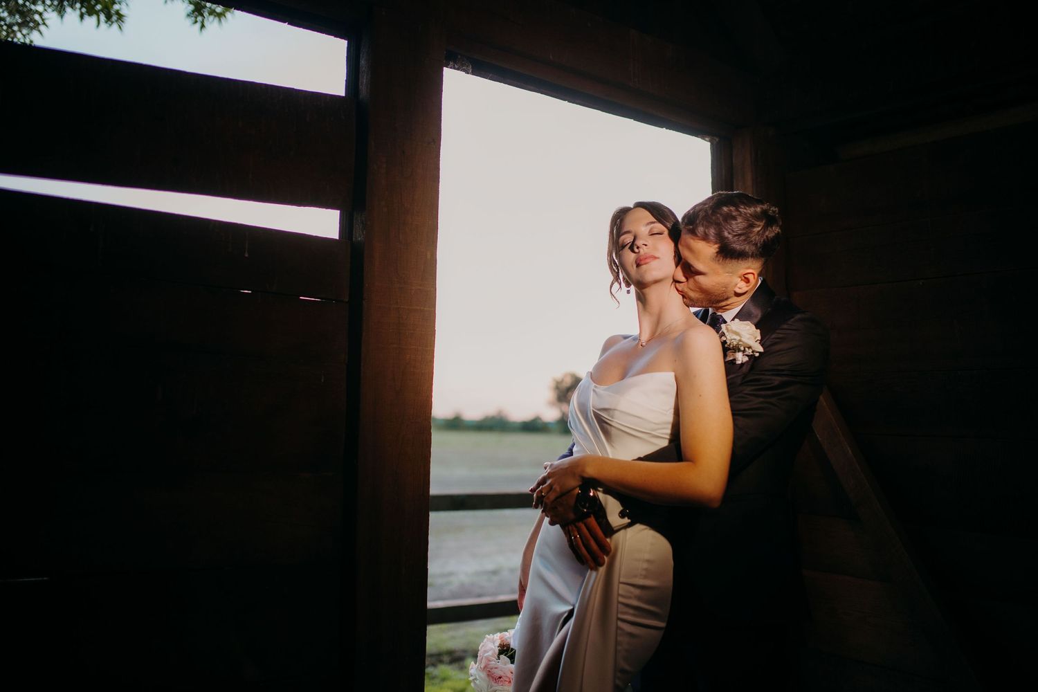 A romantic couple shares tender moments together during a wedding celebration at sunset.
