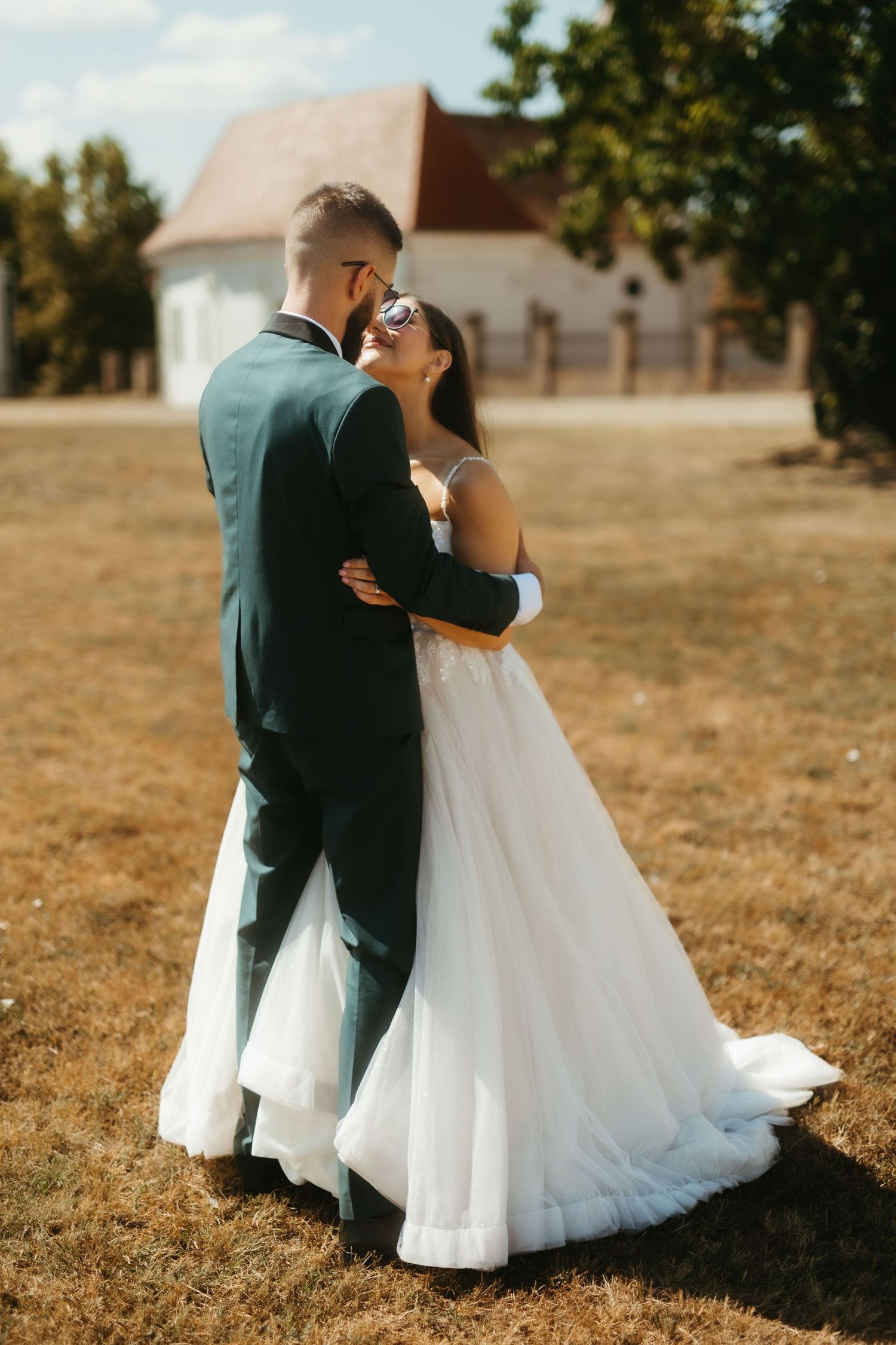 A romantic couple shares an intimate kiss in their wedding attire against a golden autumn field backdrop.