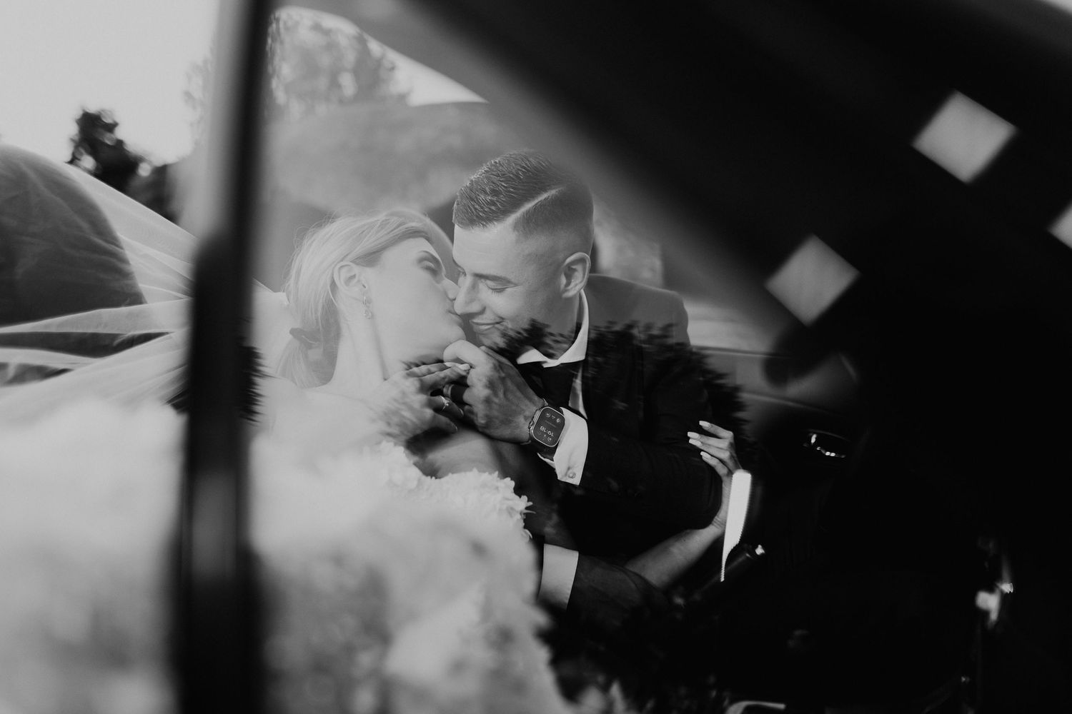Dramatic black and white photo of newlyweds in car.