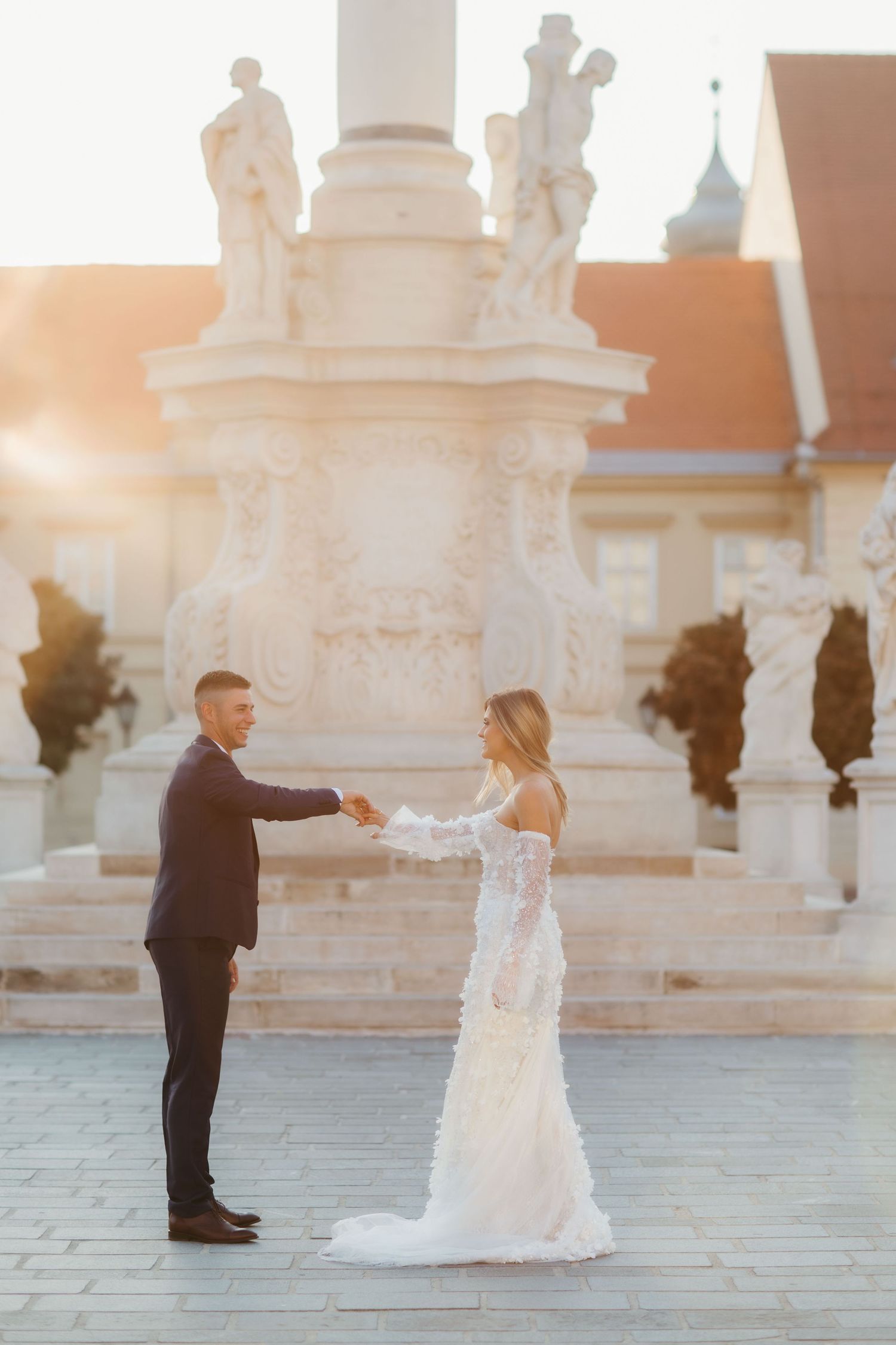 A couple dancing together in front of a classical stone monument during golden hour.