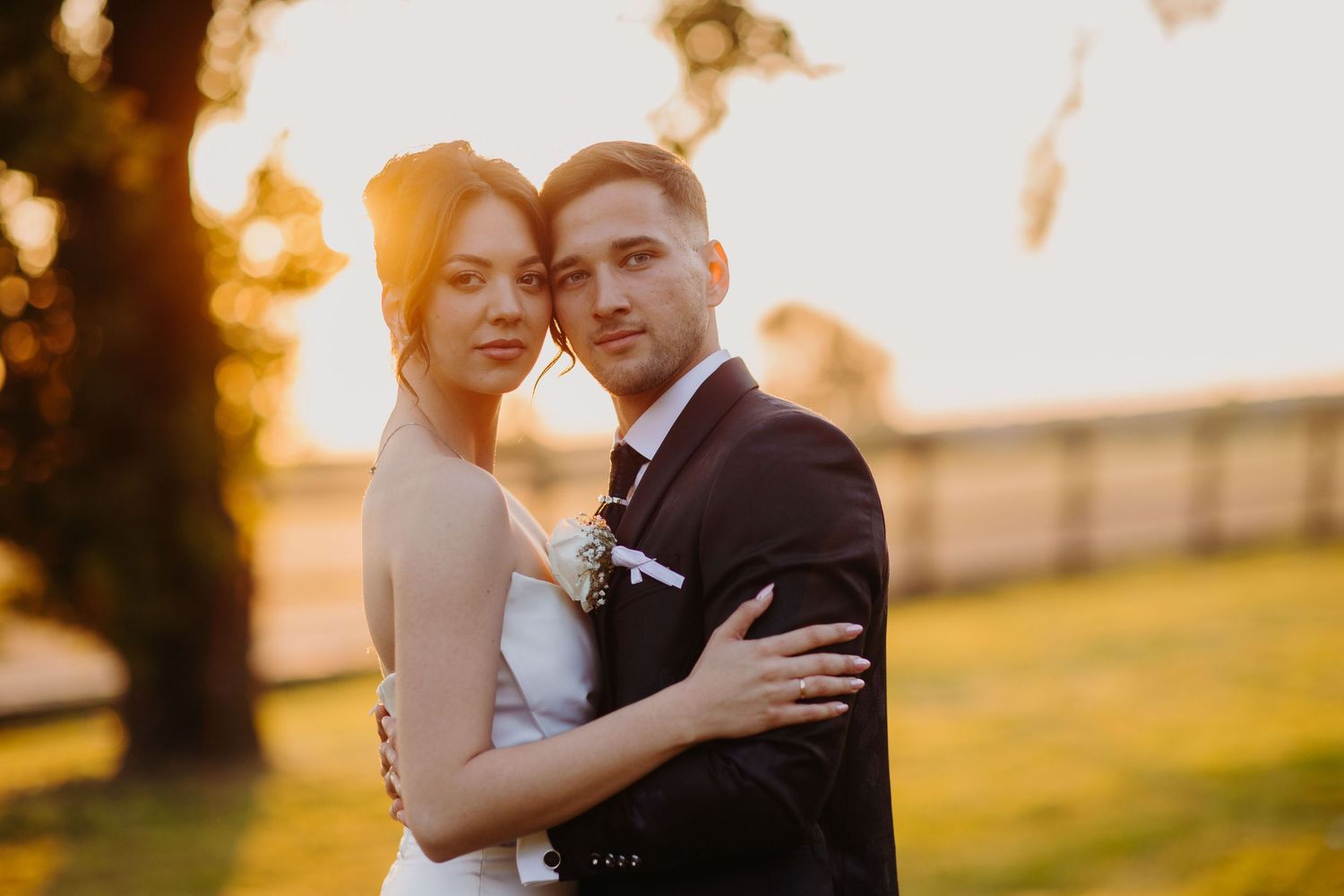 A couple embraces during a romantic sunset photo session in an outdoor field.