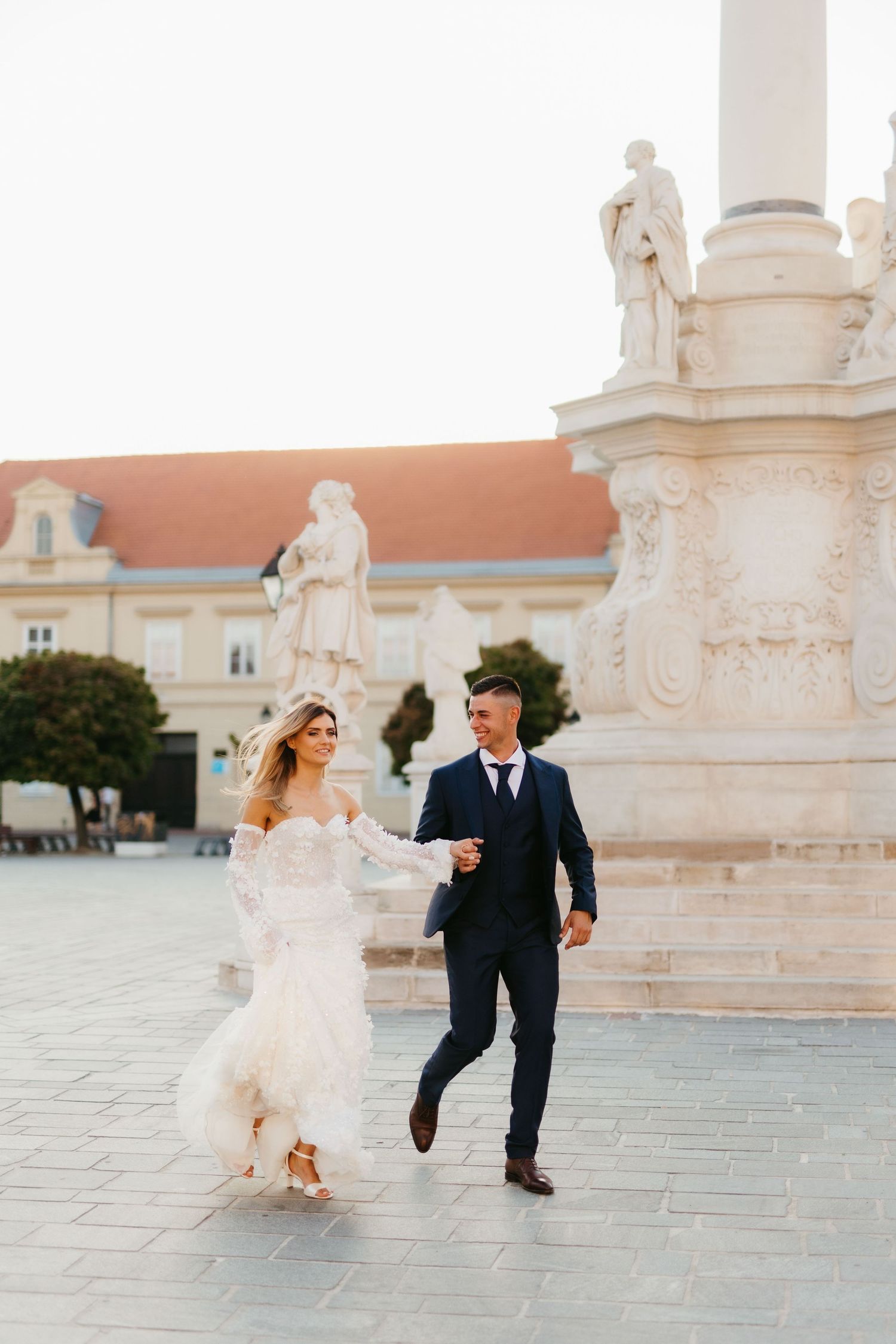 A couple runs joyfully across a historic courtyard during their wedding.