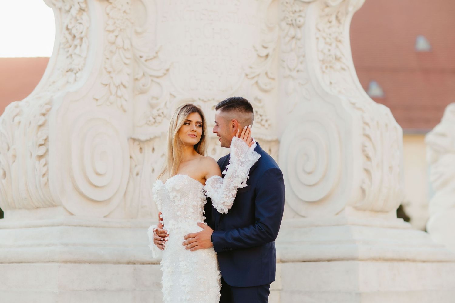 Elegant wedding portrait with couple against white classical column backdrop.
