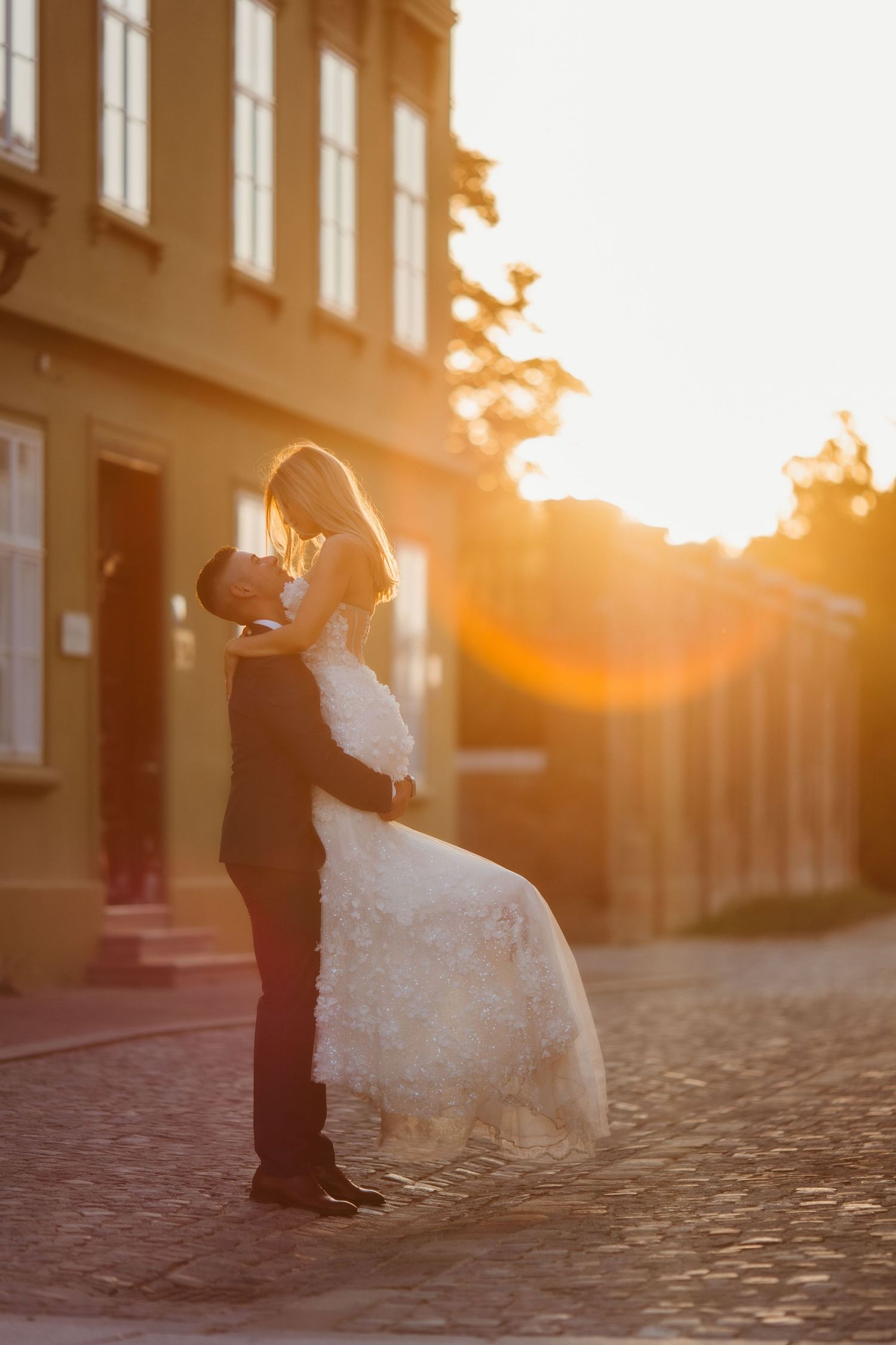 Silhouetted wedding couple sharing a romantic moment on a cobblestone street at sunset.